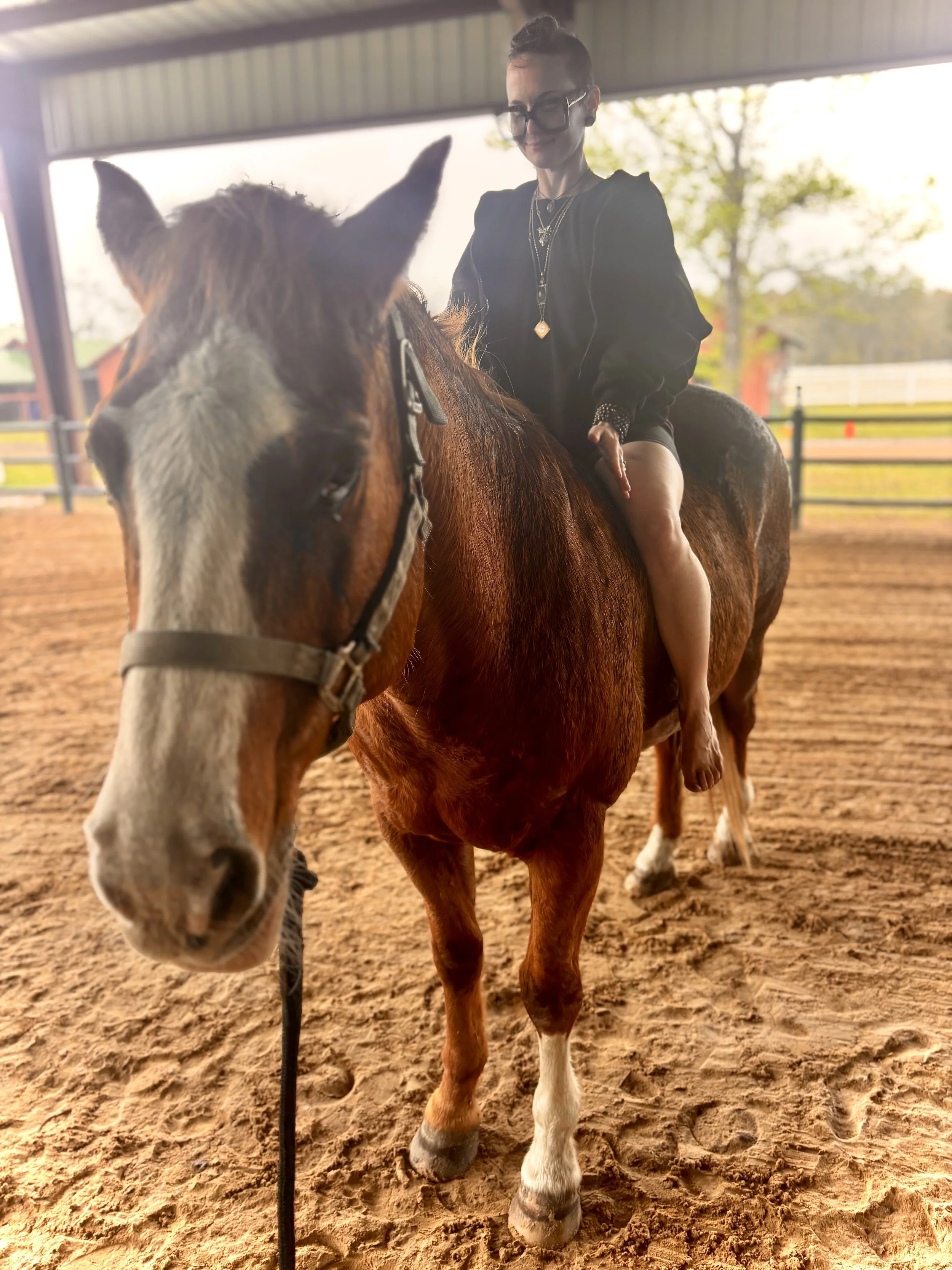 A woman riding a brown and white horse inside a covered riding arena during the daytime.