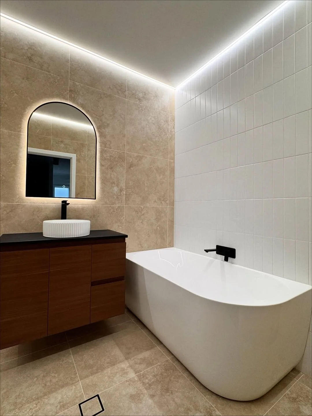 Complete bathroom fit-out showing expert installation of a modern freestanding bath and black minimalist tapware.
