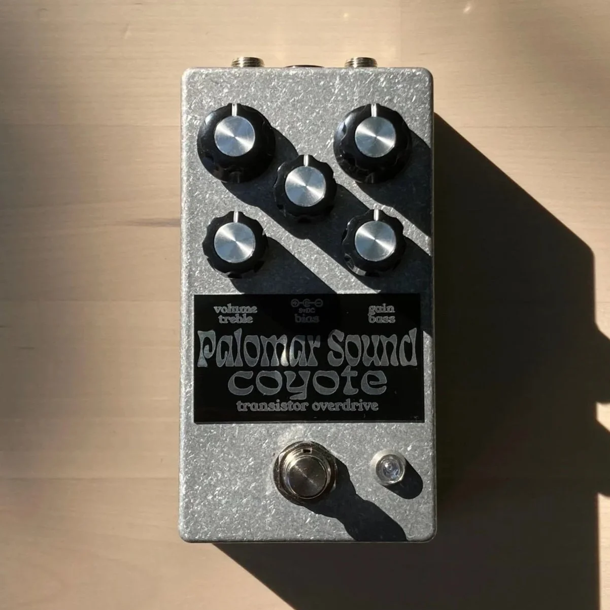 Guitar effects pedal labeled 'Palomar Sound Coyote,' with controls for volume, treble, bass, bias, and gain, featuring five black knobs and a footswitch at the bottom.