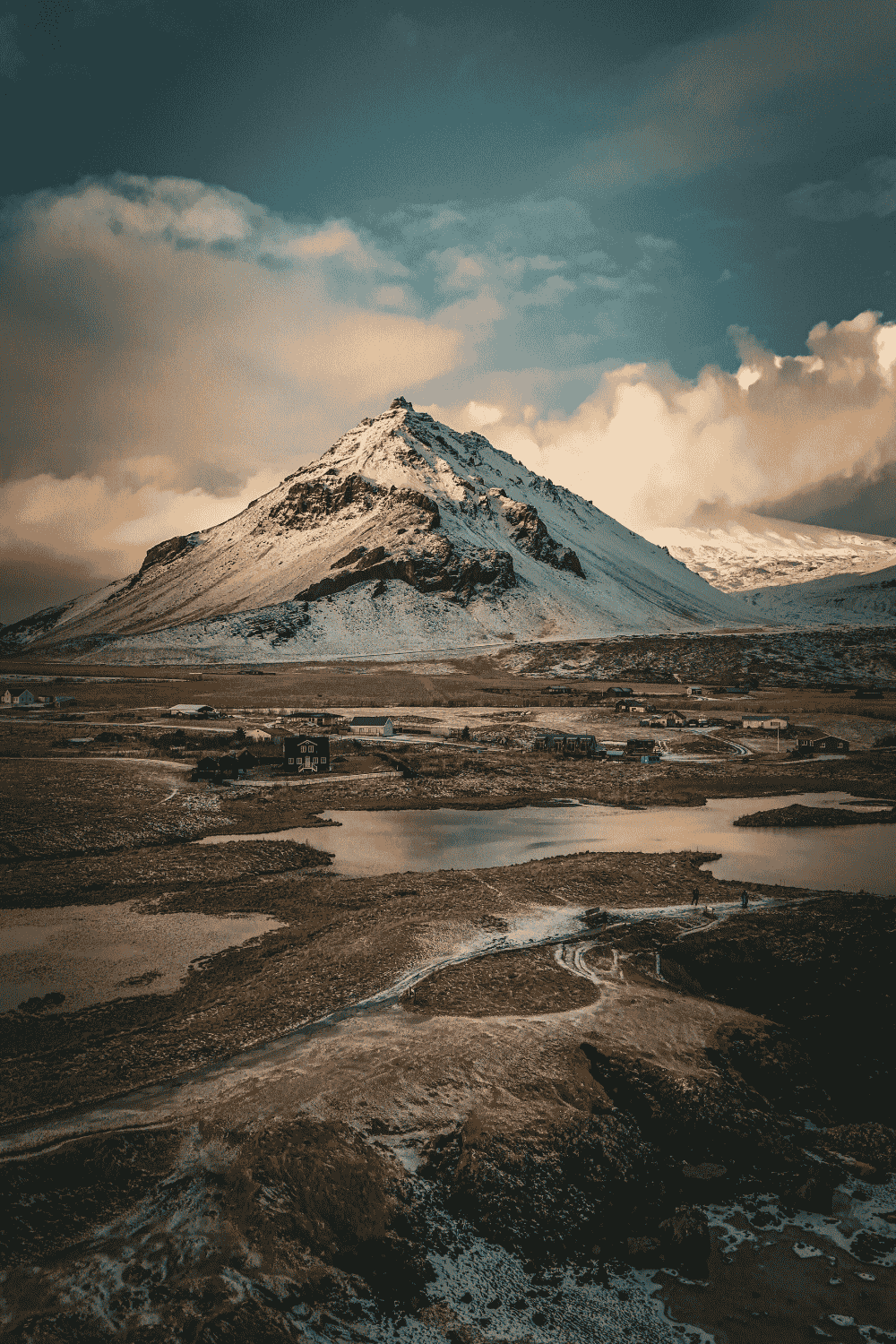 Iceland mountain landscape with snow-covered peak and scenic countryside under dramatic sky