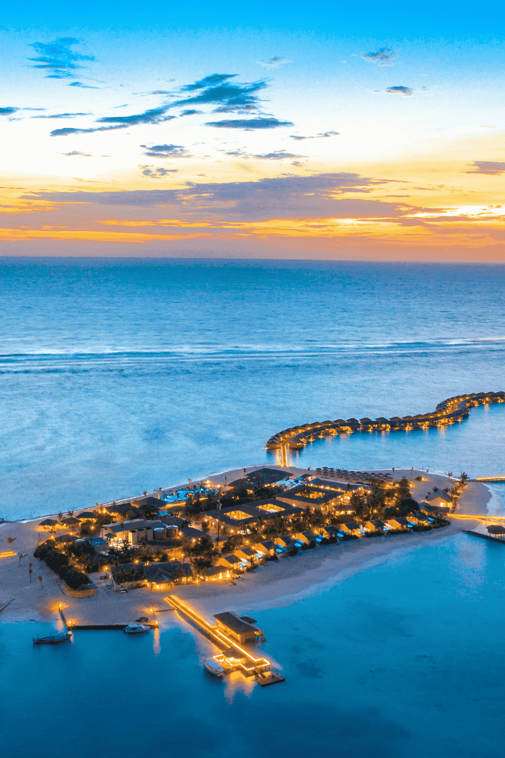 Maldives tropical island resort with overwater villas and turquoise ocean at sunset