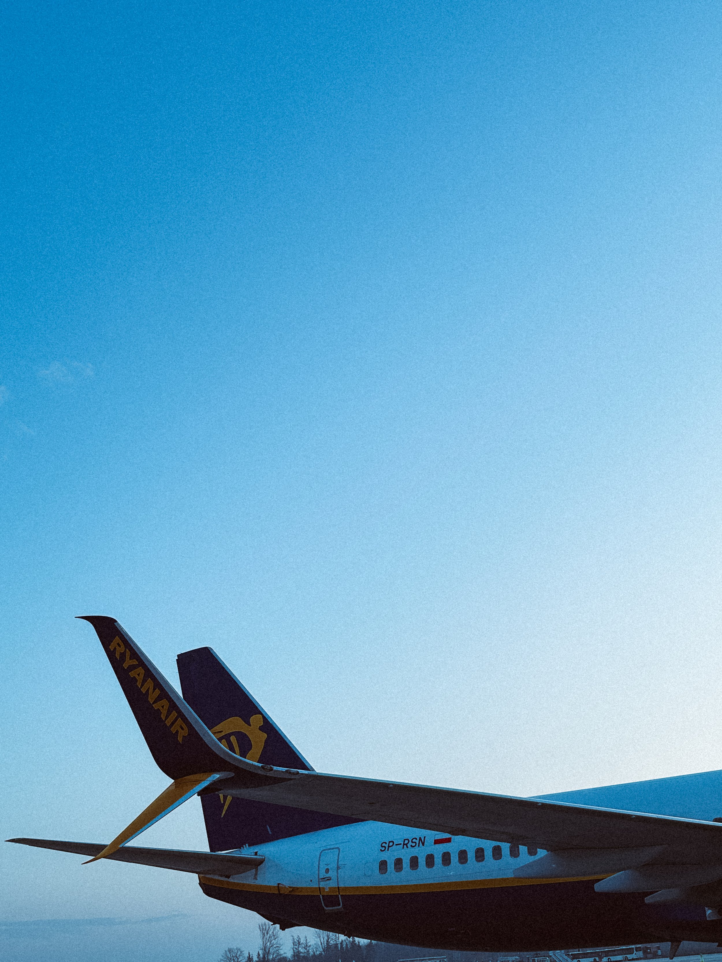 Fetta di cielo azzurro sopra un aereo Ryanair parcheggiato a terra.