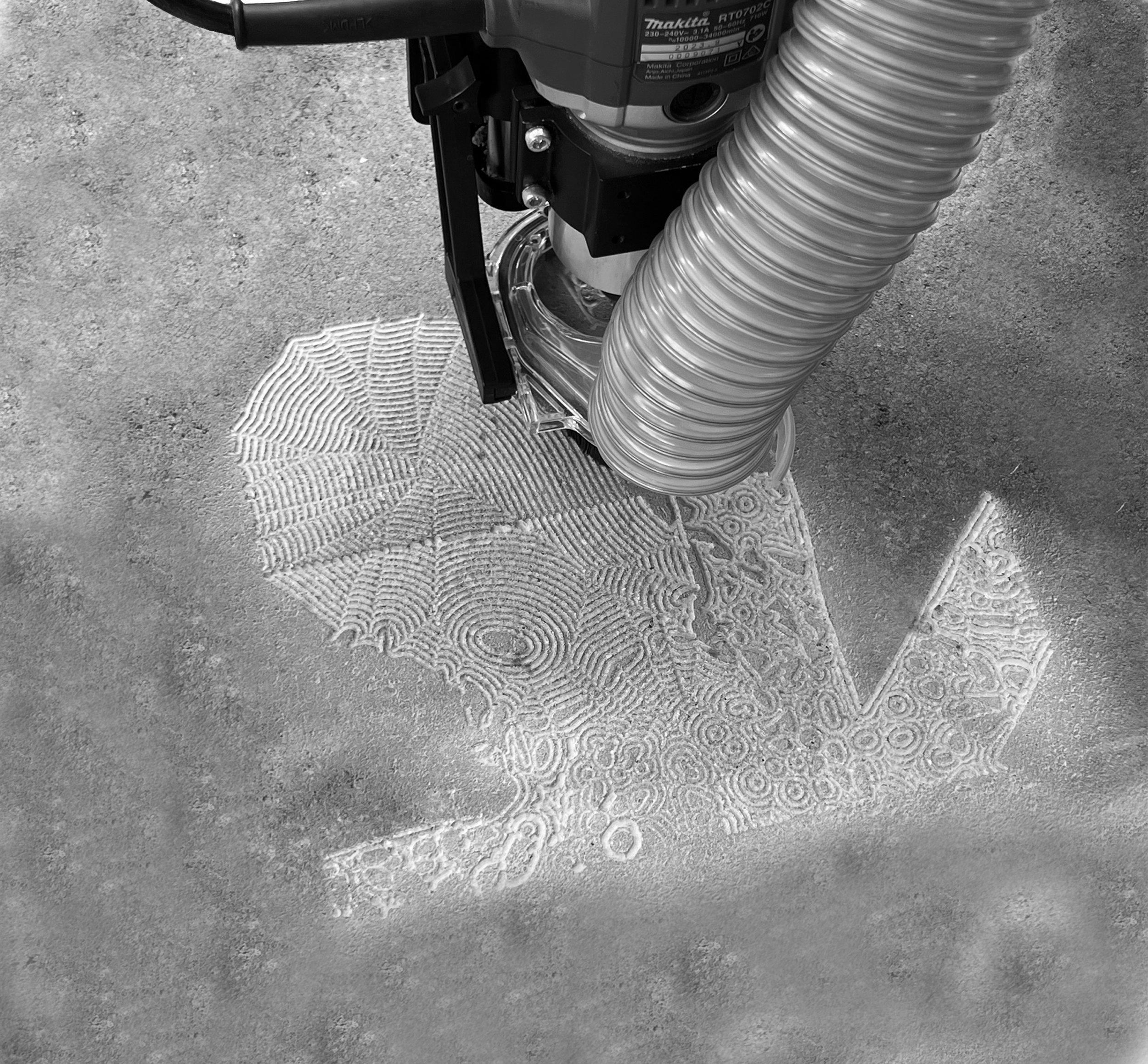 A floor cleaning vacuum machine is creating intricate, concentric patterns in the sand on the floor.