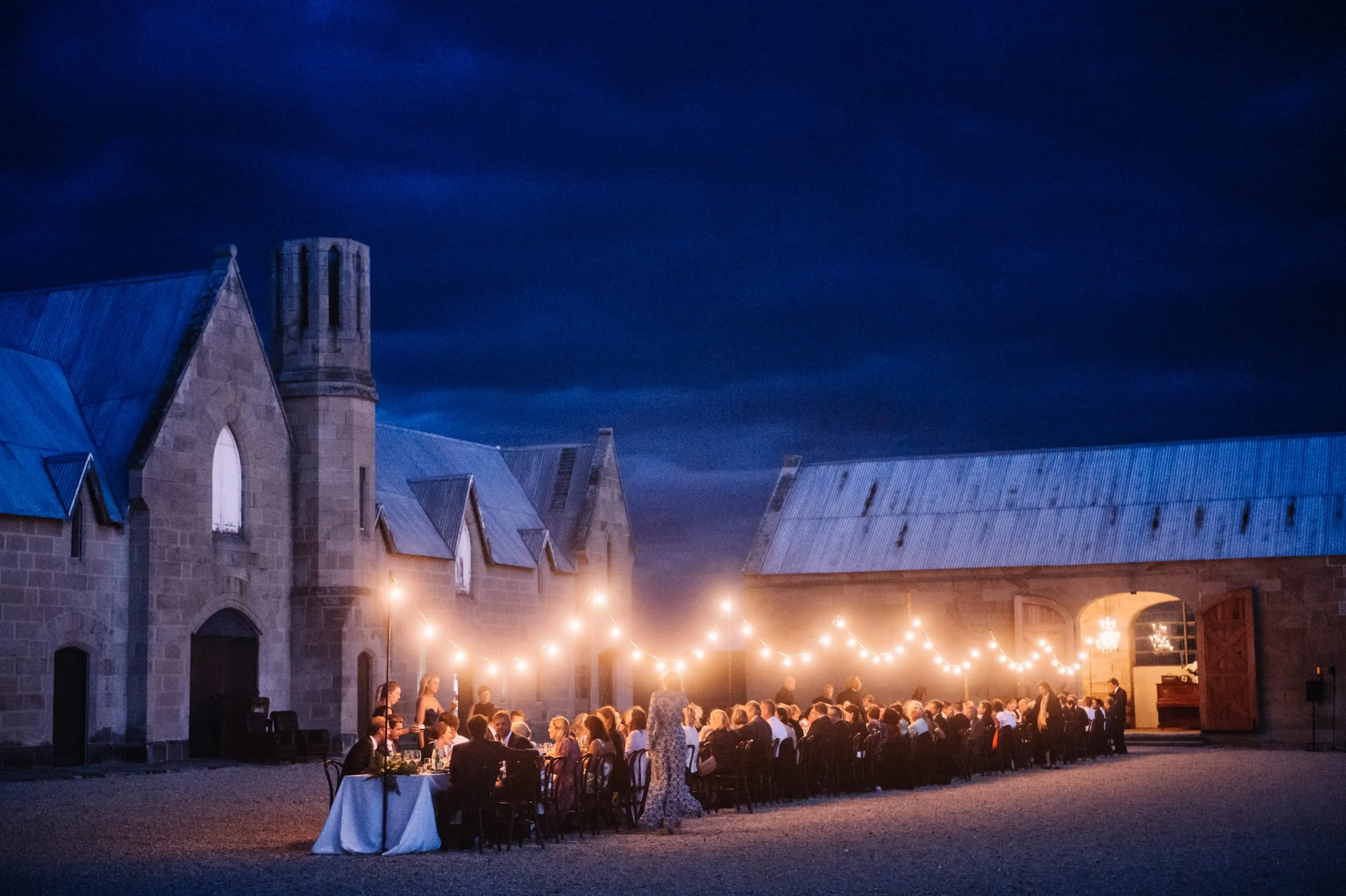 A beautiful evening wedding table at Lark Distillery with festoon lights above a long table