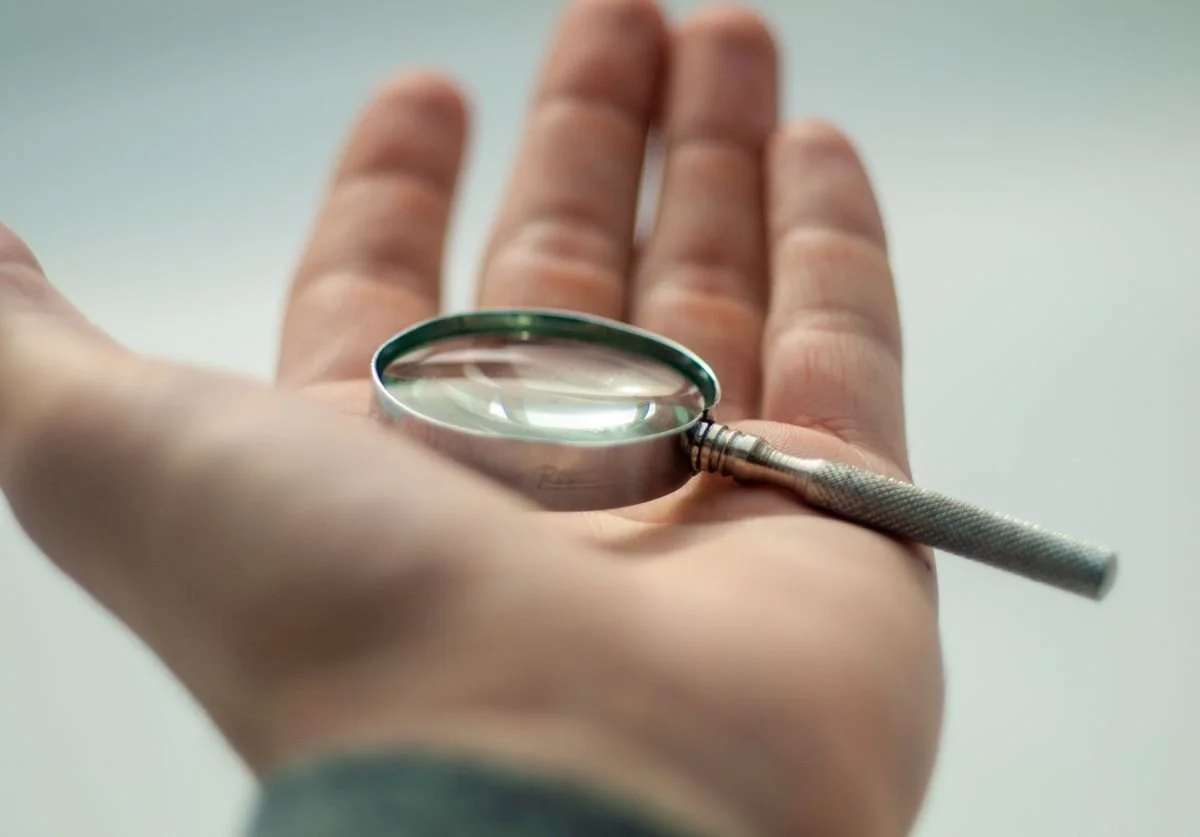 man-holding-a-magifying-glass-in-his-hand.jpg