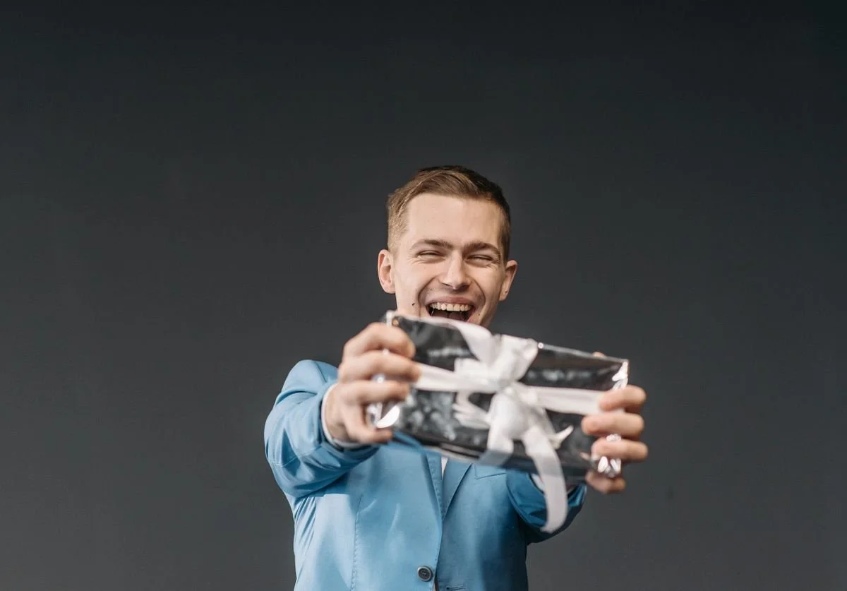 a-man-smiling-and-presenting-a-gift.jpg