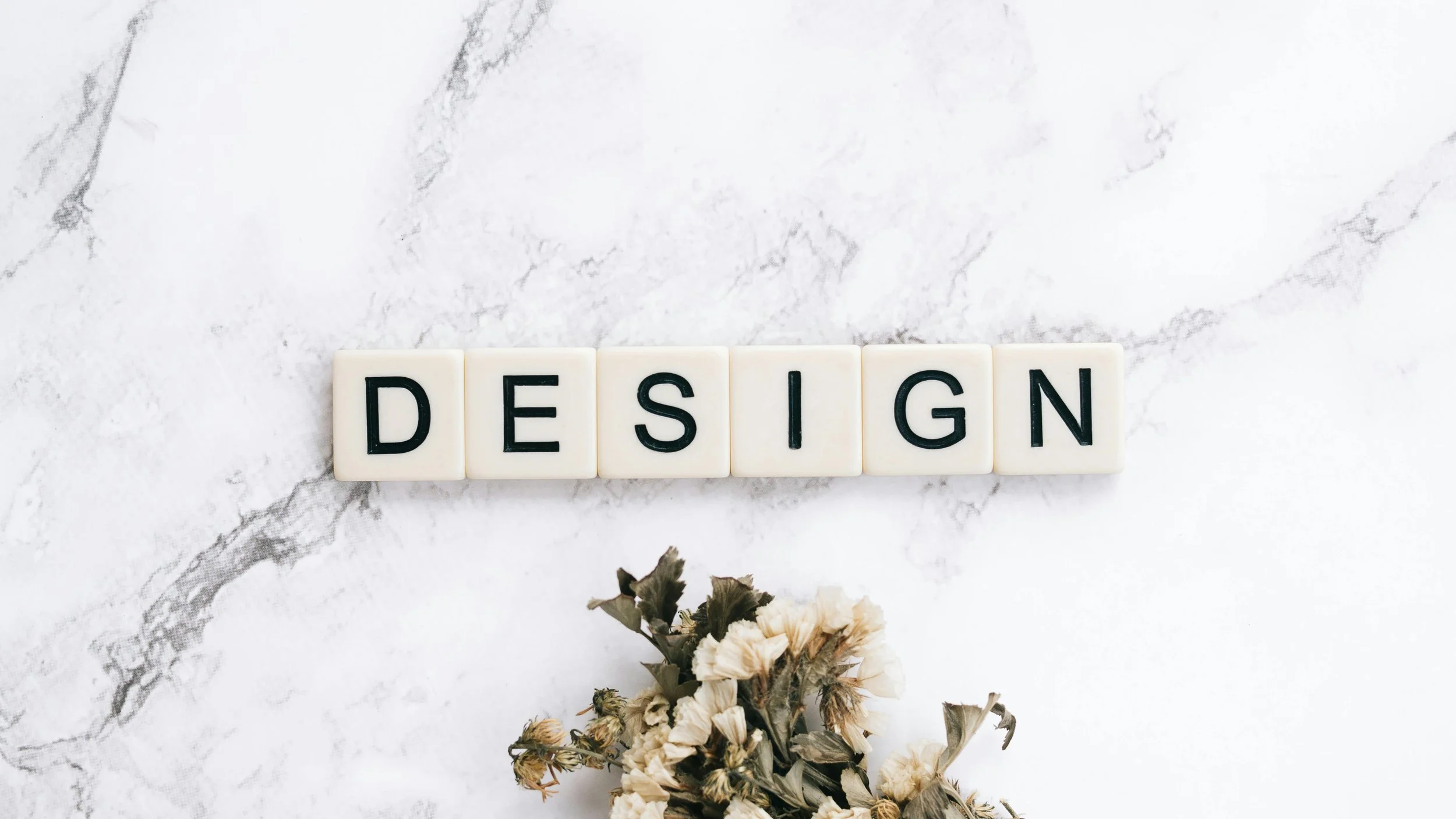 letter-cubes-that-spell-out-design-against-marble-and-pretty-flowers-for-a-wellness-website.jpg