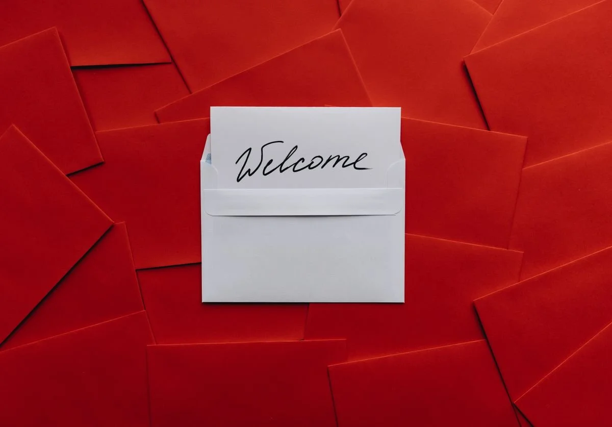 a-invitiation-on-white-paper-with-the-word-welcome-written-in-a-white-envelope-with-many-red-envelopes-in-the-background