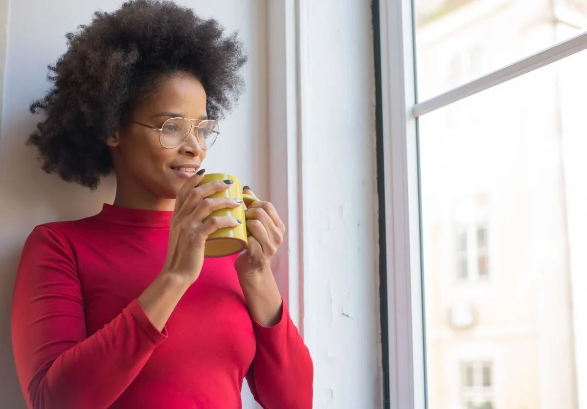 woman-looking-out-of-window-while-sipping-from-a-mug.jpg