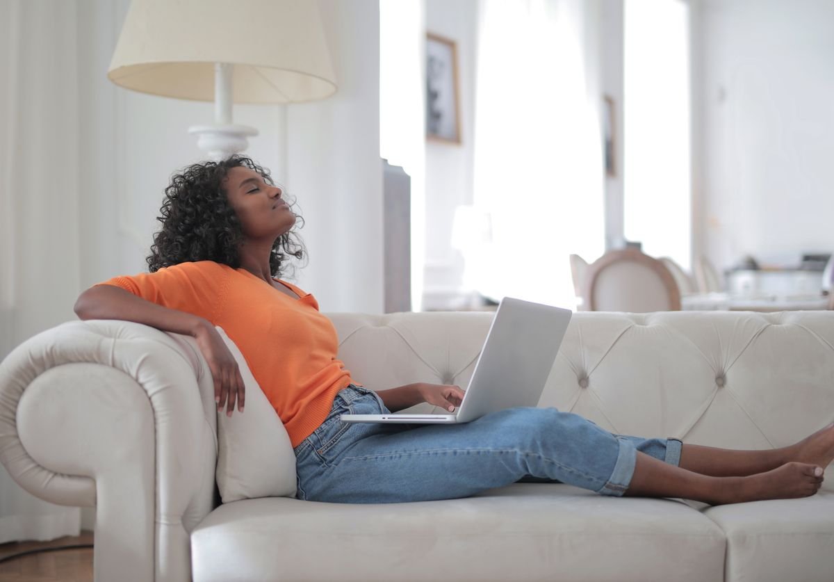a-woman-laying-on-a-couch-looking-comfortable-while-using-laptop-massage-therapy-nomadic-virtual-solutions.jpg