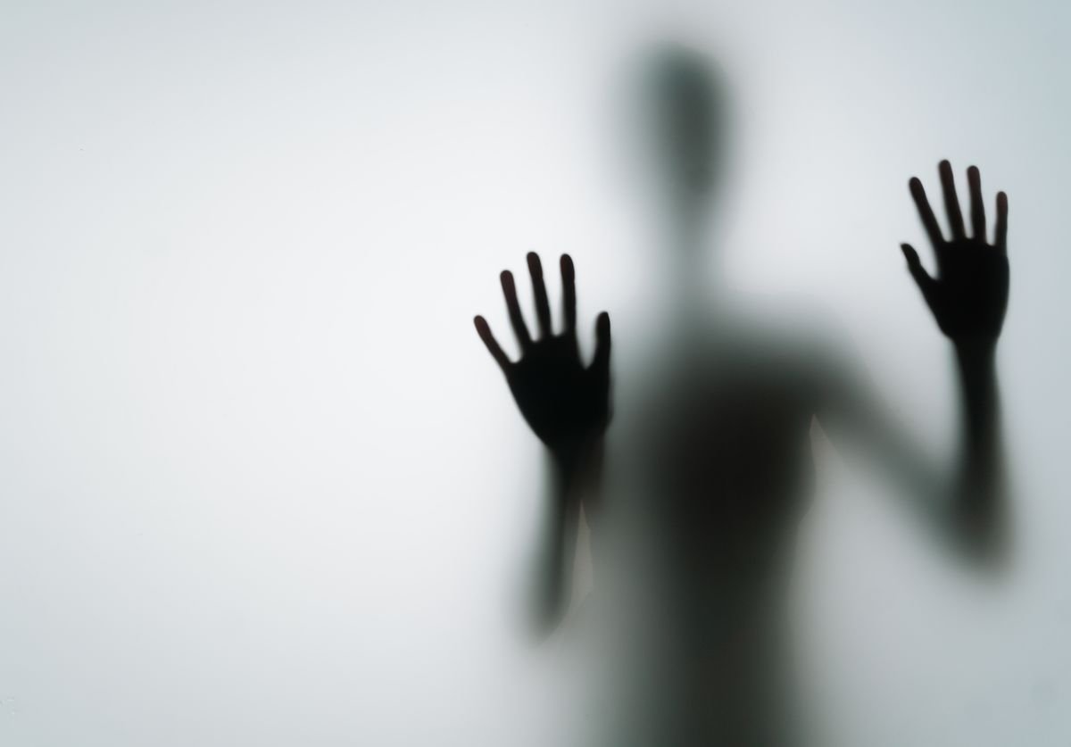 a-black-shadowy-figure-presses-up-against-a-stain-glass