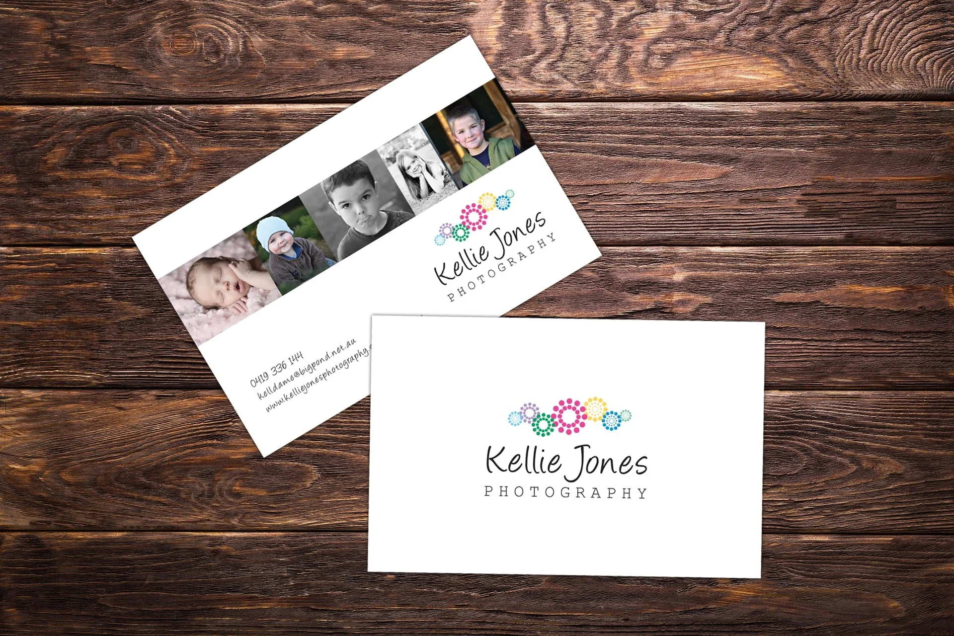 Business cards for Kellie Jones Photography featuring colorful gear-shaped logo and photos of children on a wooden surface.