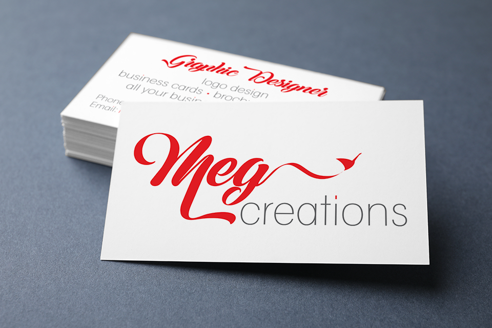 Business cards for Meg Creations with a red and black logo on a gray surface