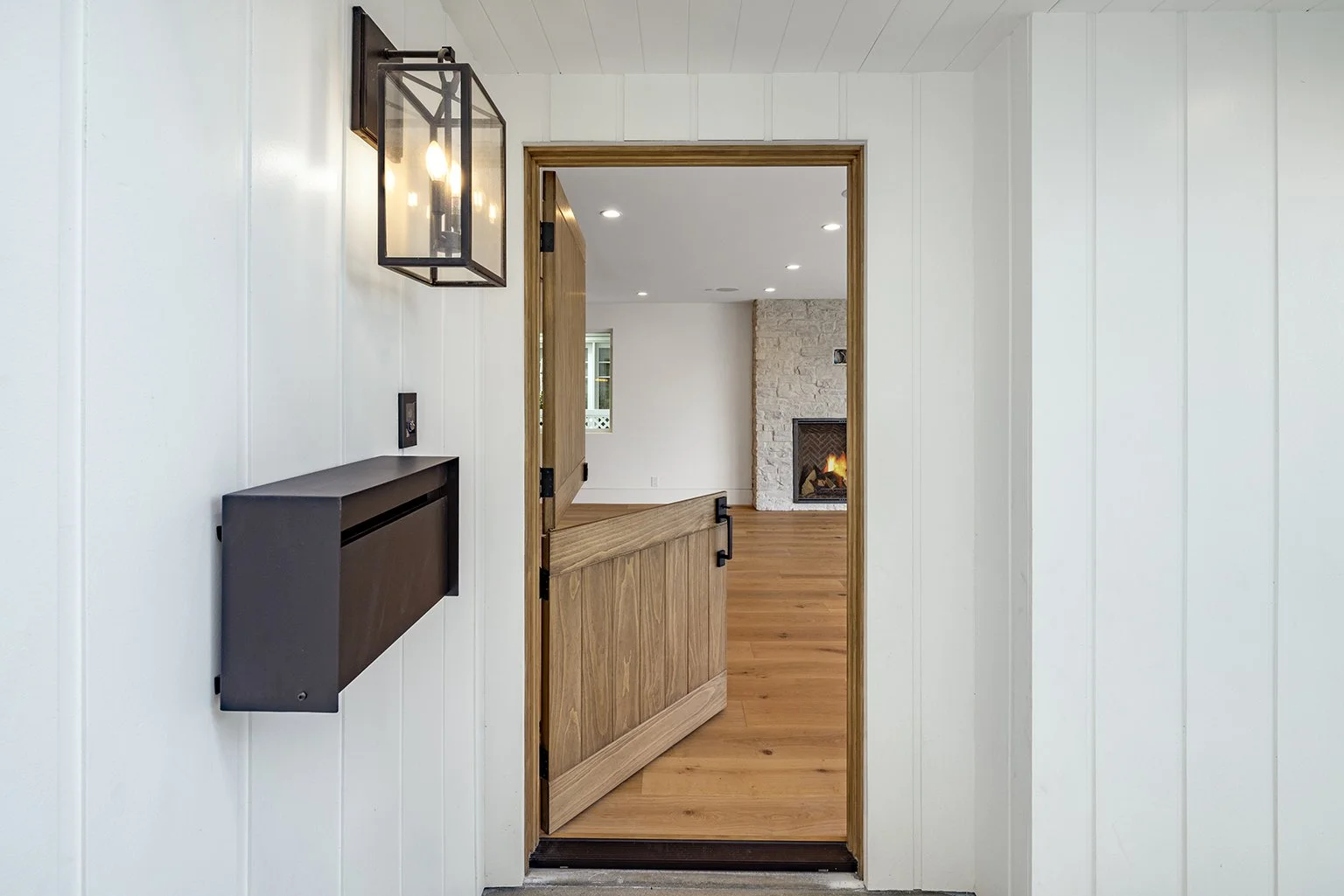 View through a doorway into a living room with a white stone fireplace and hardwood floors.