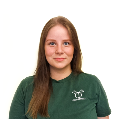 Porträtt av en ung kvinna med långt brunt hår, bär en grön T-shirt med en logotyp.