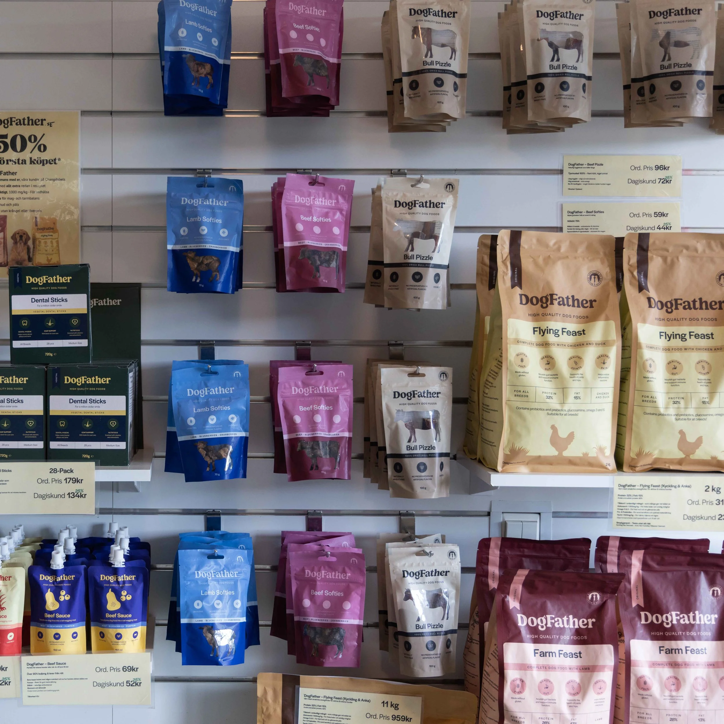 Hyllplantering med olika hundfoder i påsar från märket DogFather, inklusive lamm-, ärtbiff- och Bully Pizzle-foder, med prisskyltar och produktinformation.