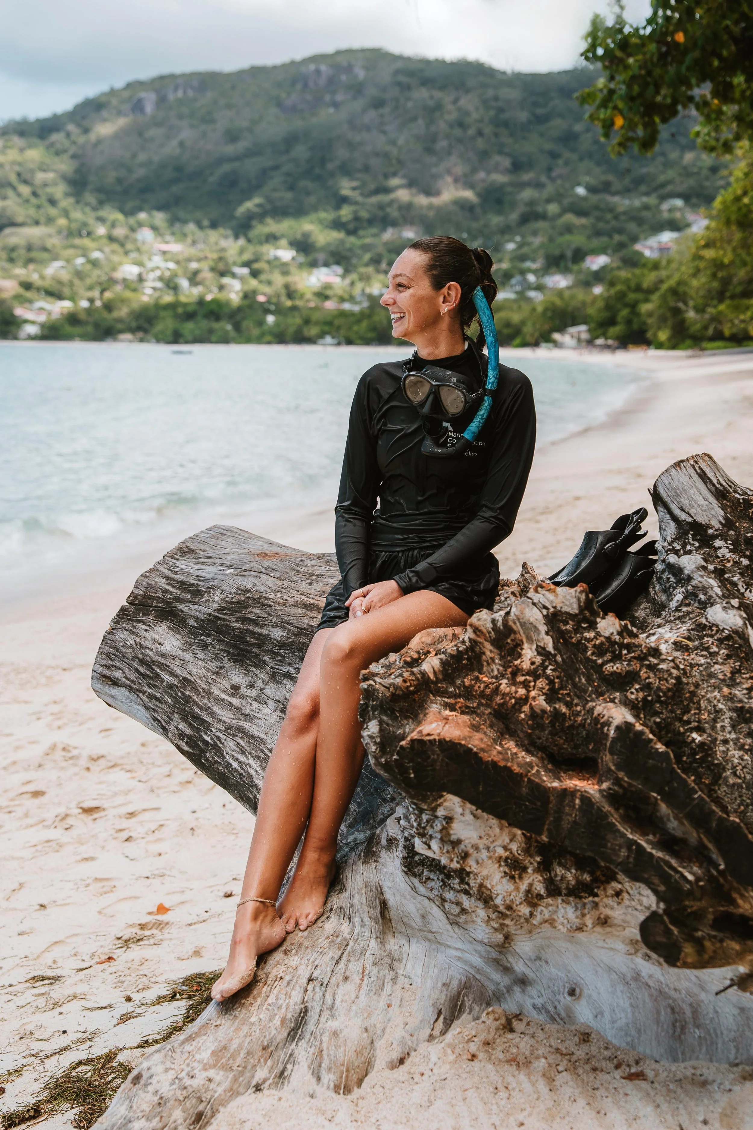 Young man sitting on a bench, wearing a gray polo shirt and light-colored pants, with a shadow cast on the wall behind him.