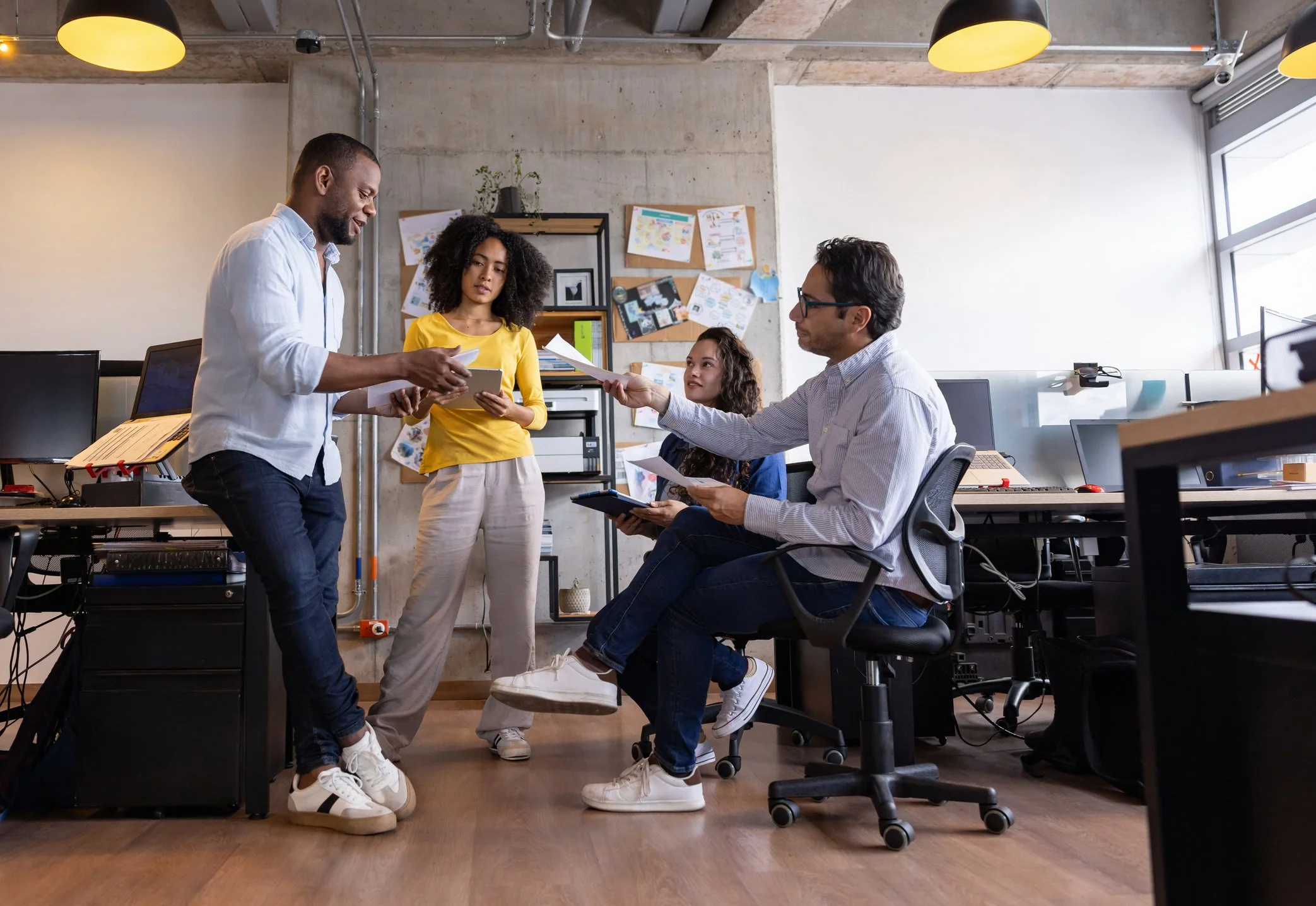Un grupo de personas en una oficina discutiendo y compartiendo documentos.