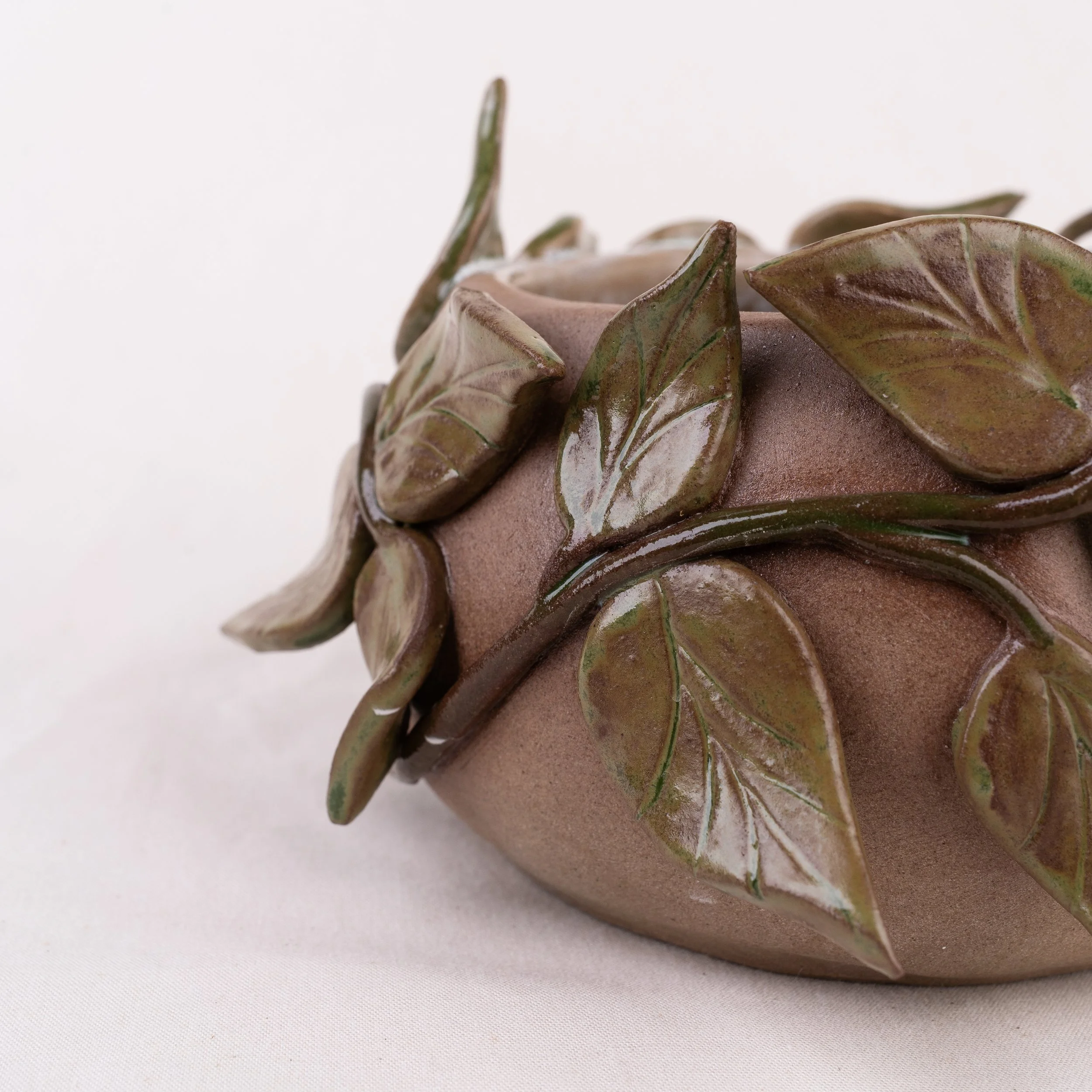 Close-up of a ceramic pot decorated with leaf designs.
