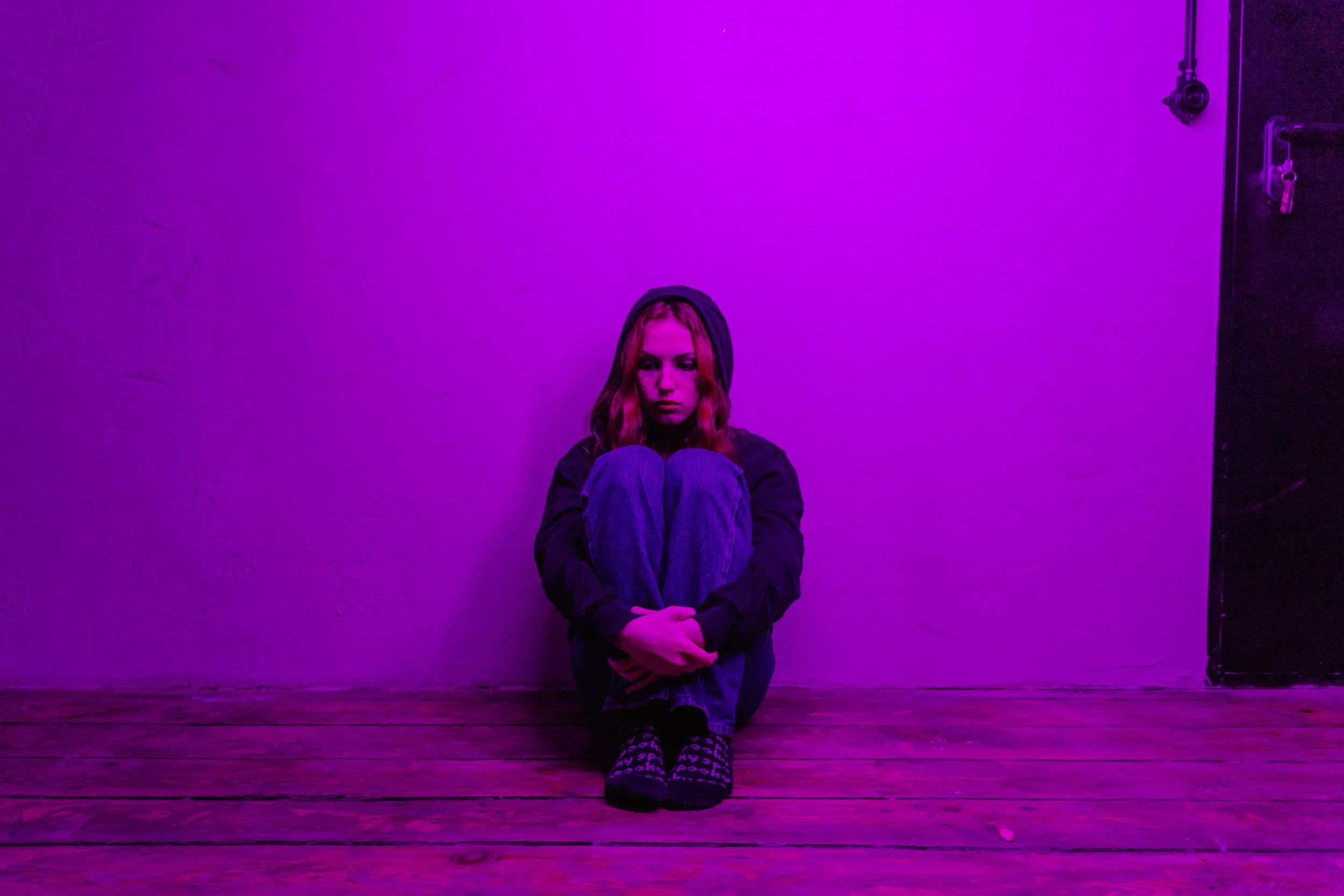 neurodivergent college student sitting in a isolated purple lighting room