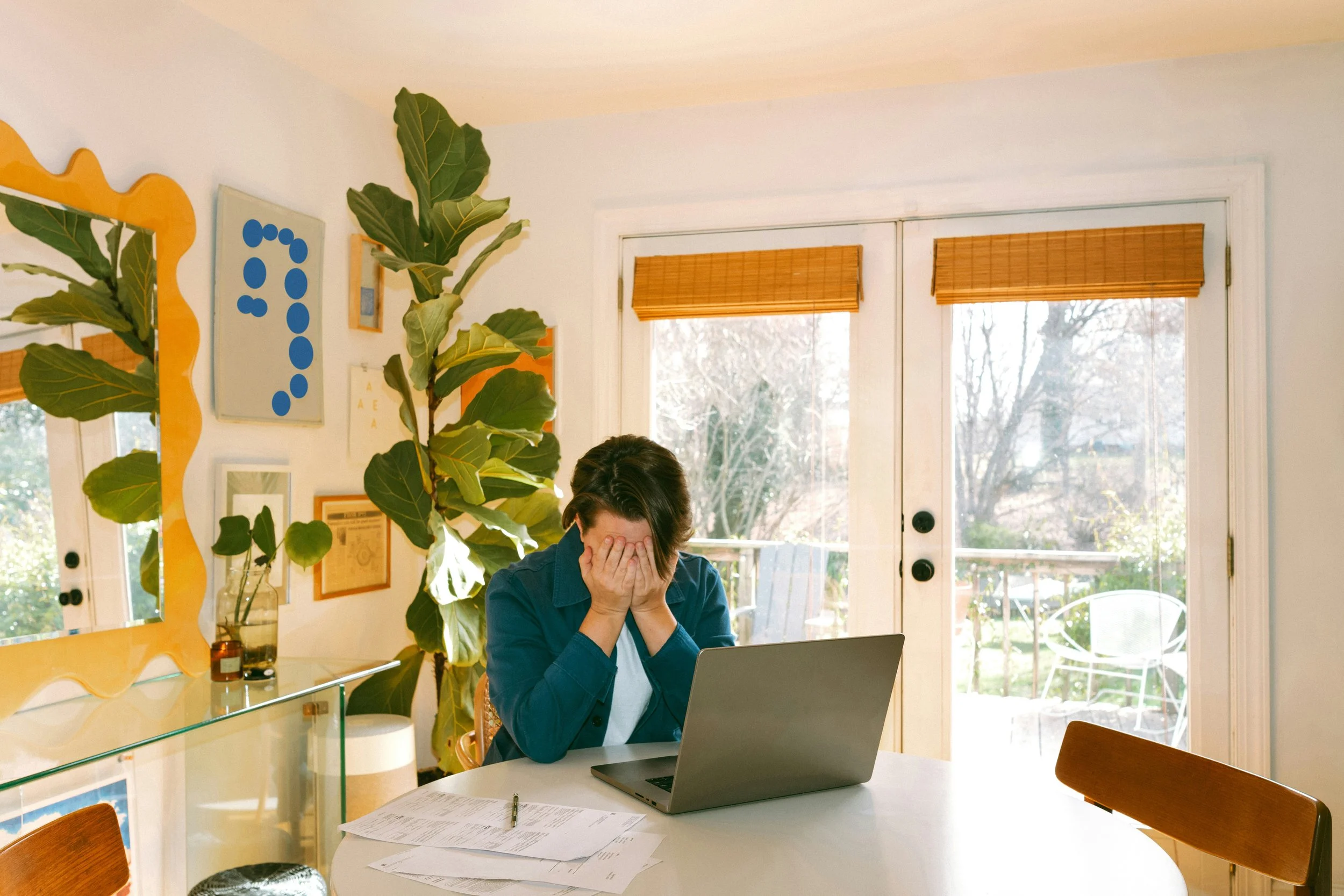 ollege student looking stressed at a laptop with bills and financial documents visible