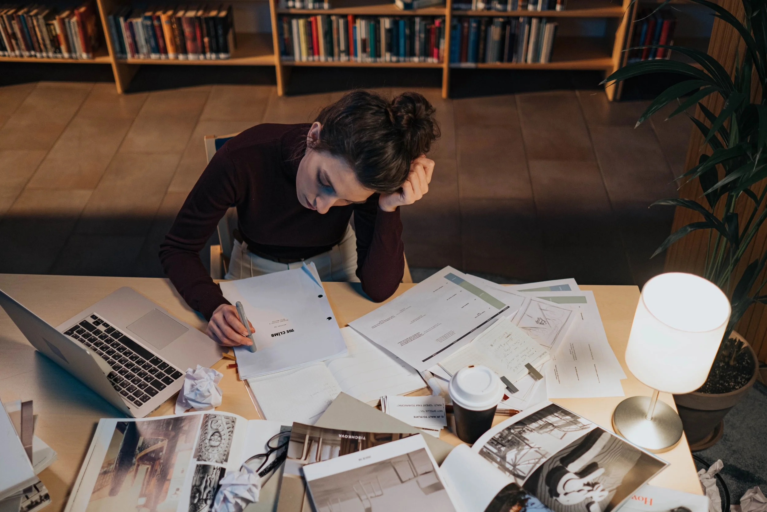 college student confused with paper scattered around her, looking stressed
