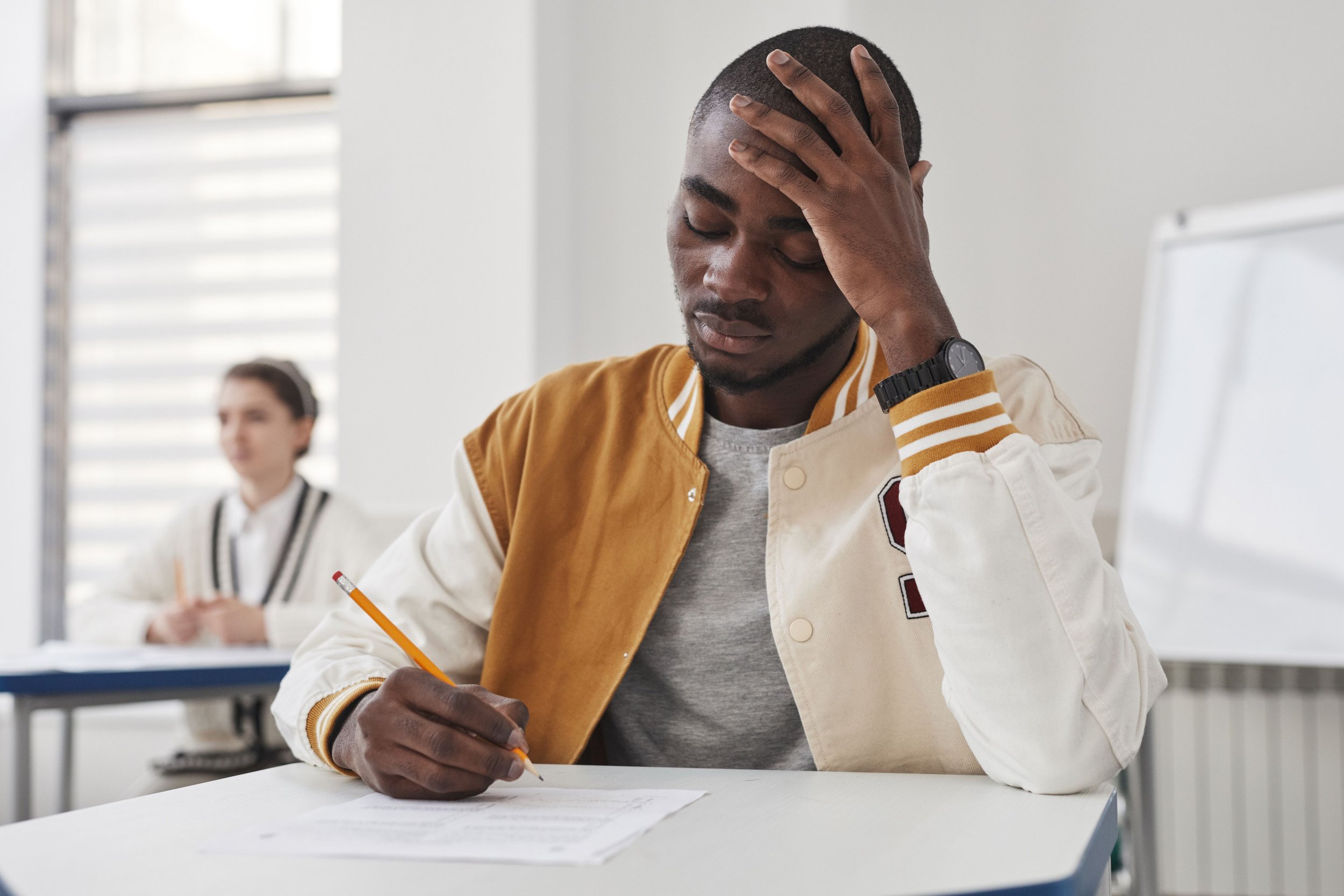college student staring at exam paper looking worried