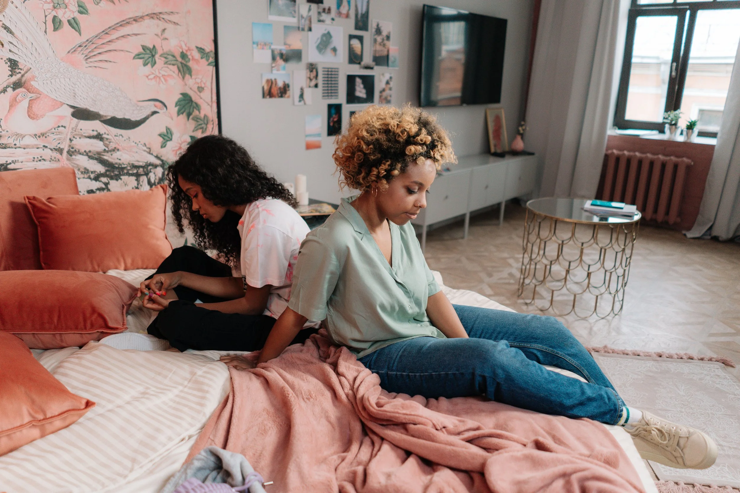 two college students in a dorm room at a distance from each other, visible tension between them