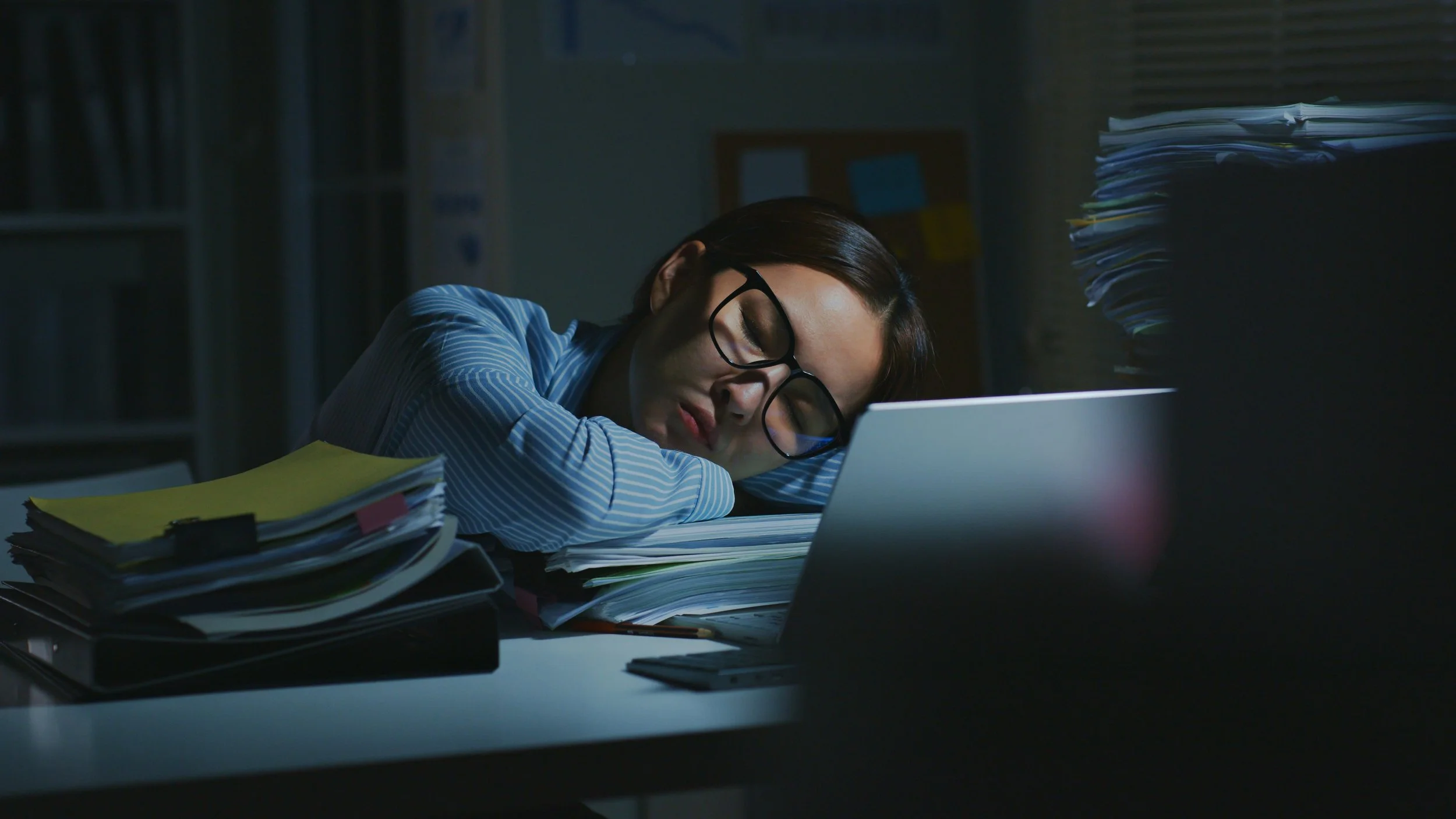 college student hunched over desk surrounded by books