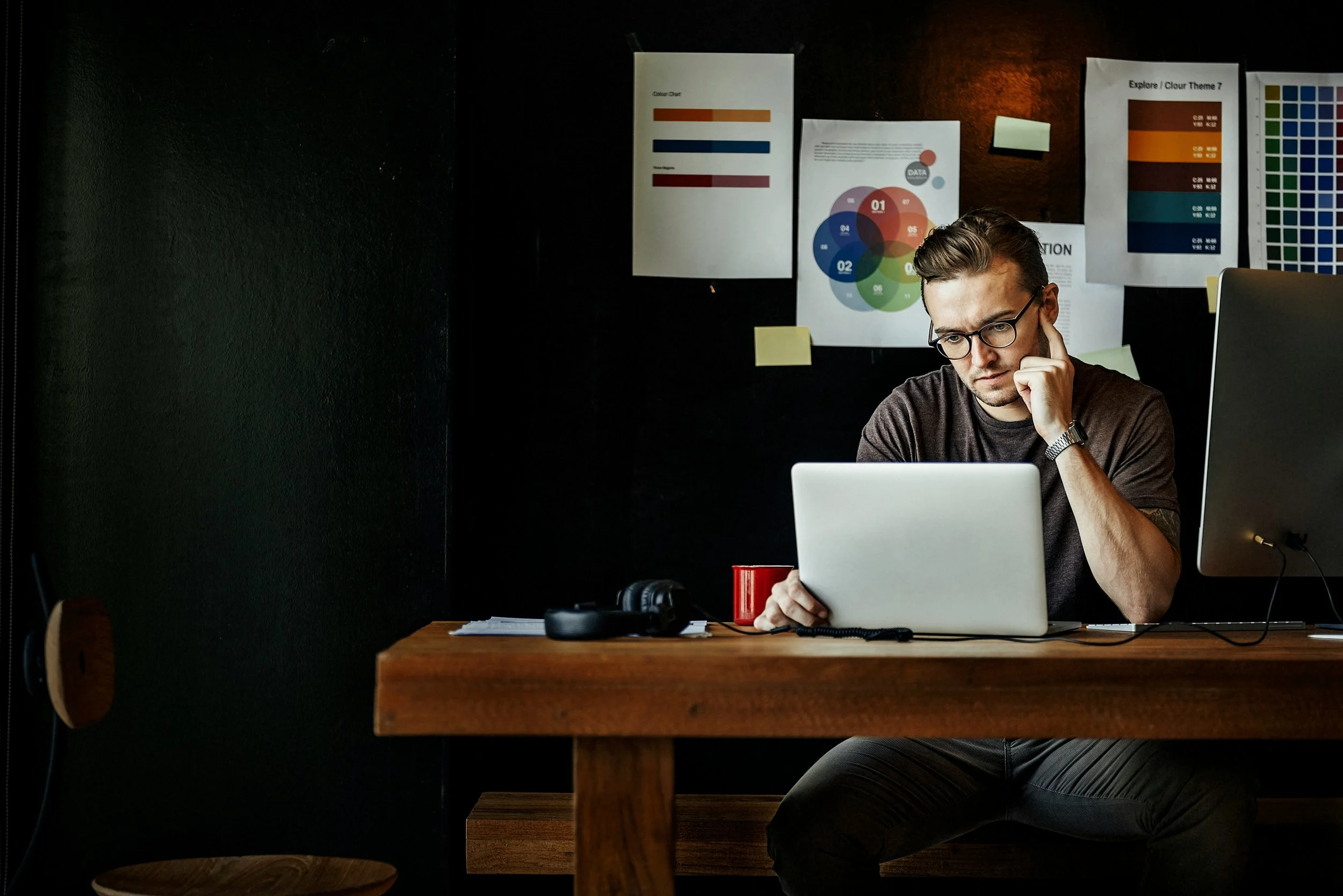 college student sitting alone looking at laptop, looking hesitant and uncertain