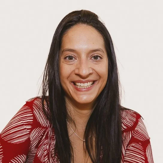 Headshot of smiling female tutor with long curly brown hair.