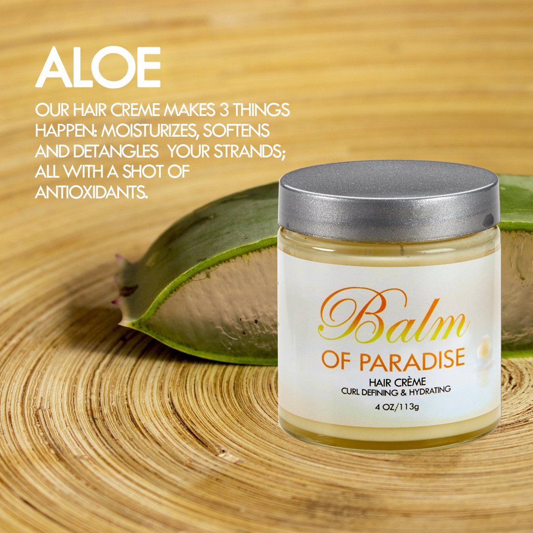 A jar of Balm of Paradise hair crème with a partially cut aloe vera leaf behind it, placed on a wooden surface.