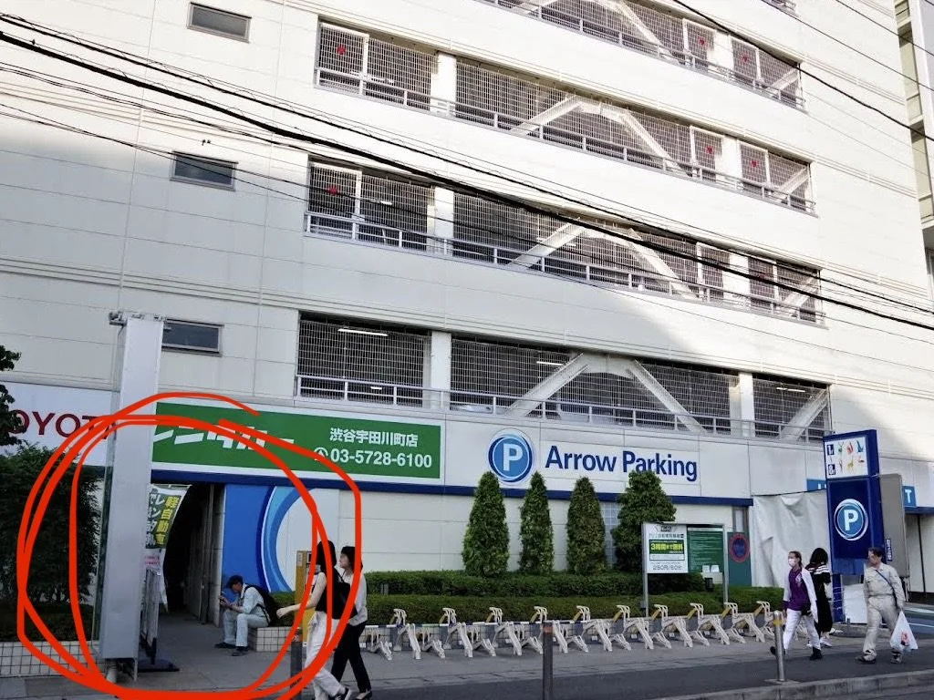 People walking and sitting outside Arrow Parking garage in front of a building with multiple floors and a parking sign.
