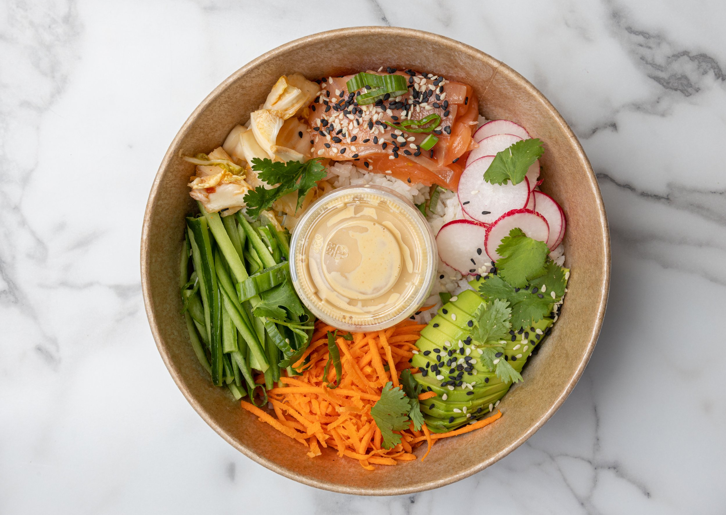 Bowl of assorted fresh vegetables and sashimi with sesame seeds, radish slices, and a small container of dipping sauce. Delicious, healthy, light lunch.