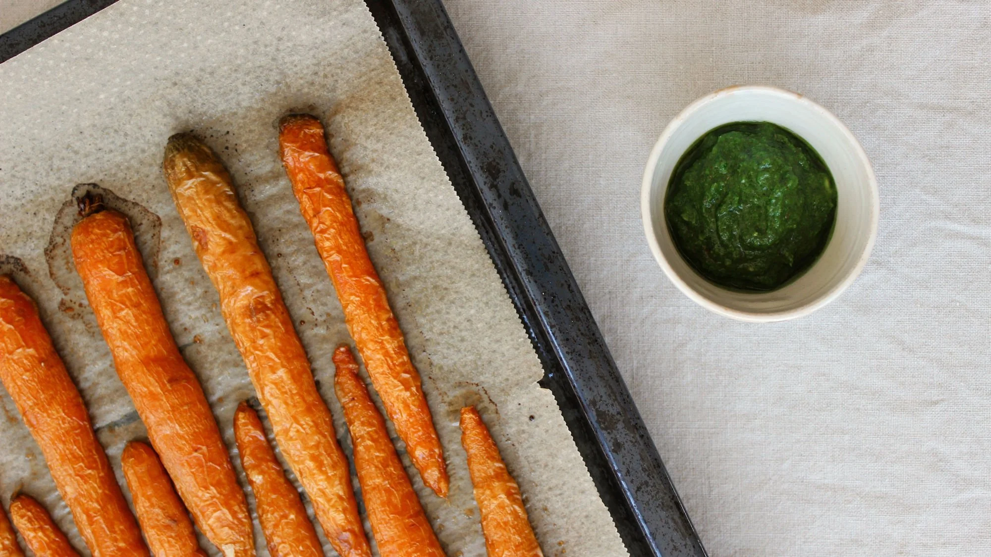 Karotten auf Backblech liegend und eine Schale mit Dill-Pesto.