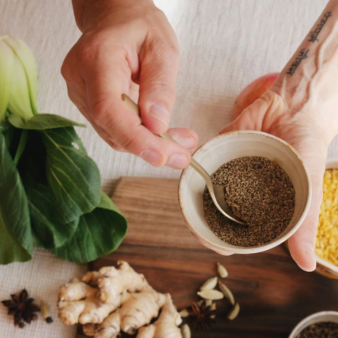 Hände mit ayurvedischen Gewürzen und Mangold