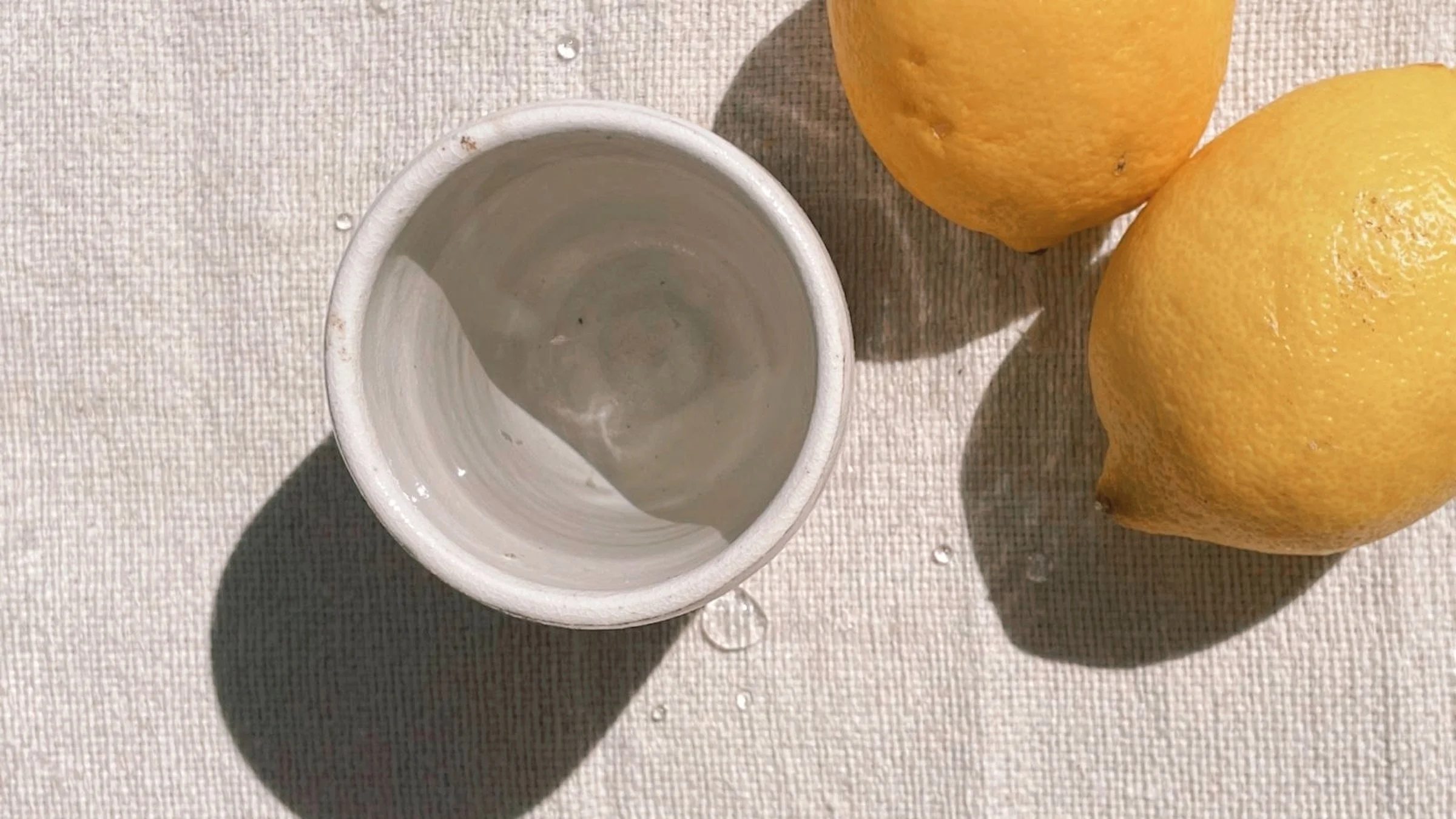 Keramikbecher mit Wasser und Zitronen