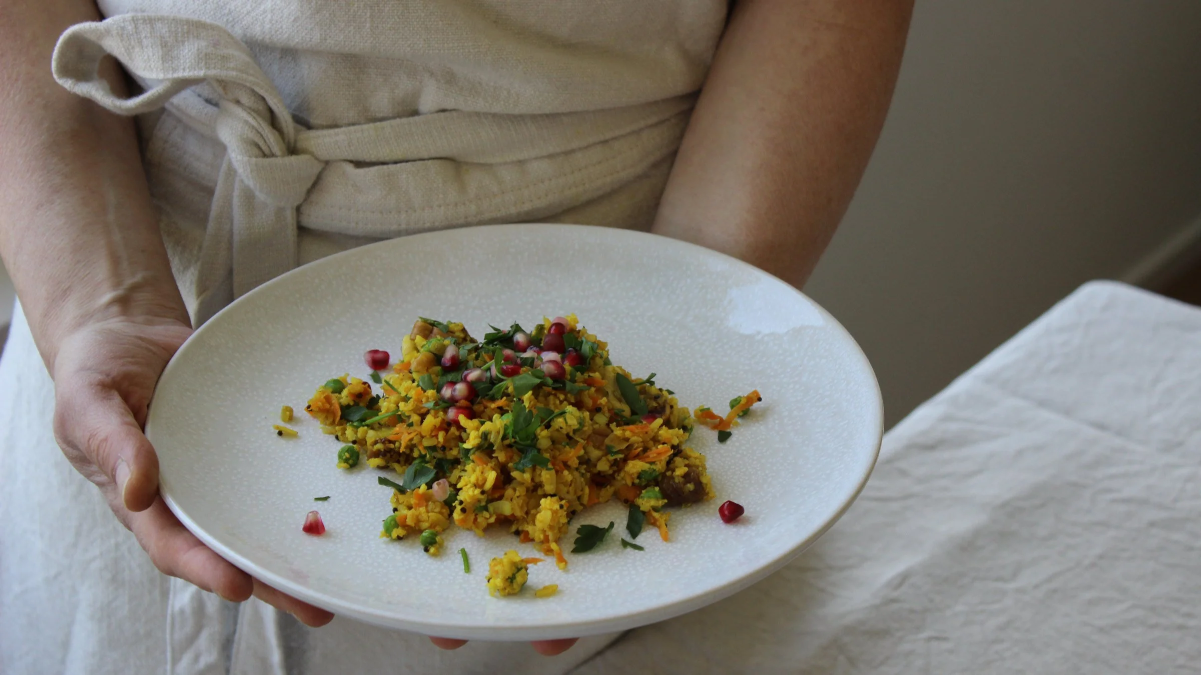 Hände halten Teller mit ayurvedischem Poha