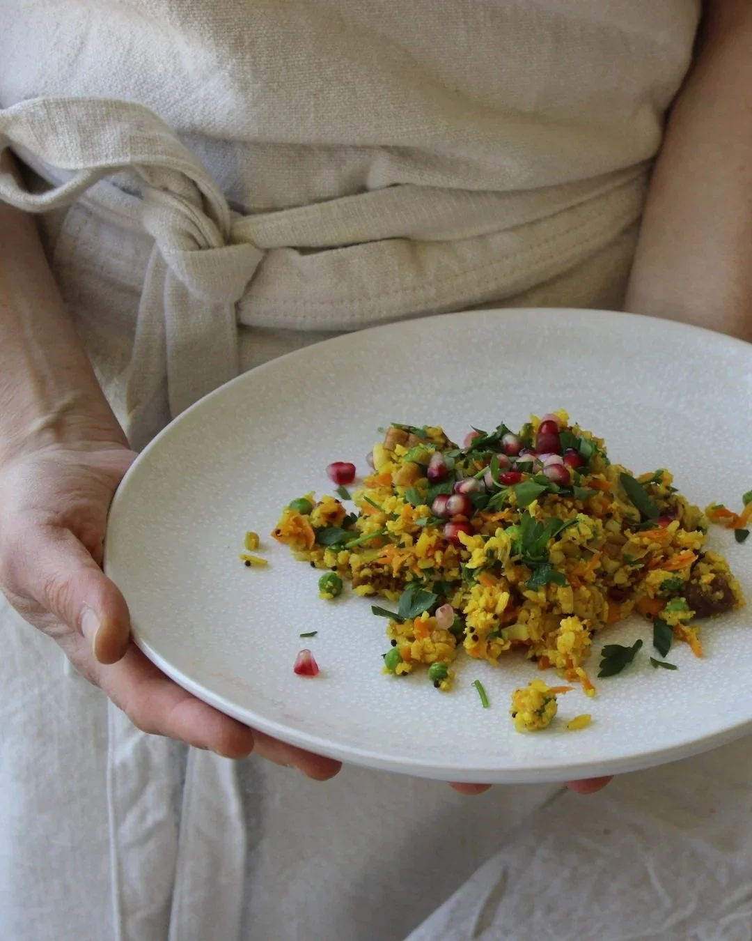 Hände halten ein Poha-Gericht auf Keramikteller
