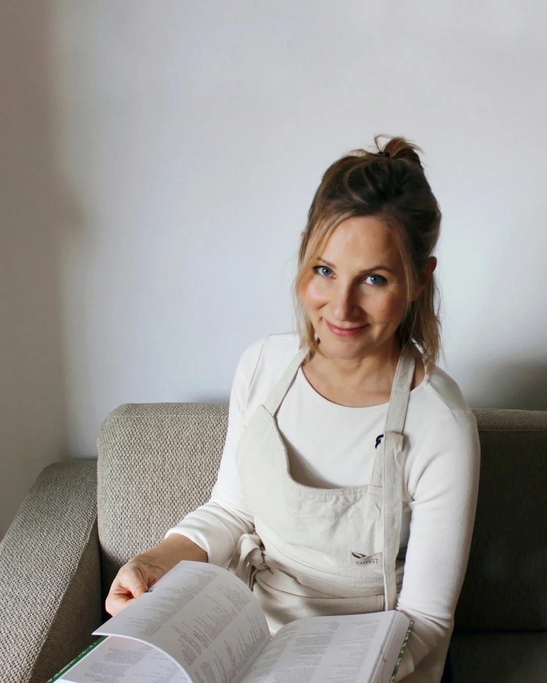 Person mit offenem Buch auf hellem Sofa