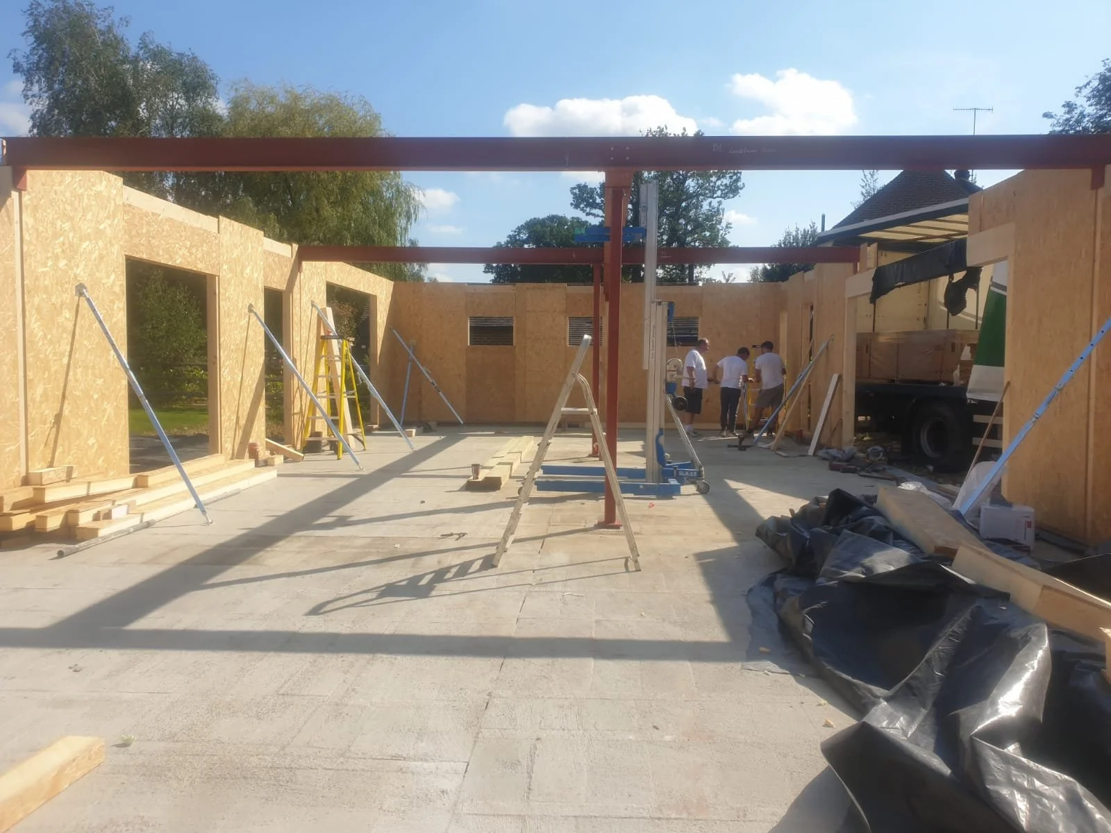 Construction site with wooden walls and workers installing the structure on a sunny day.