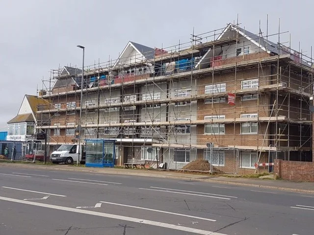 A multi-story residential building under construction with scaffolding around it.