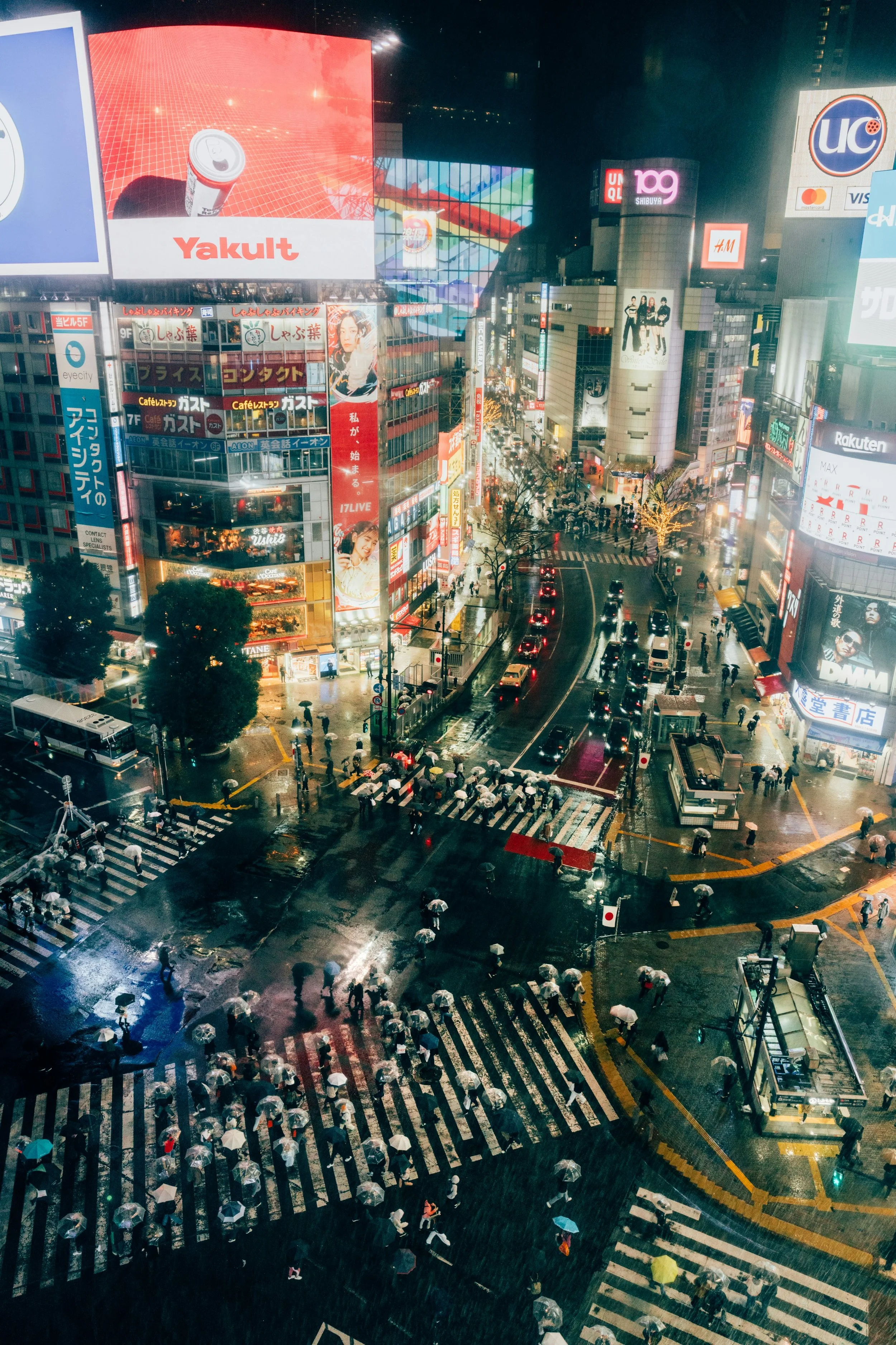 Crowds crossing Shibuya Crossing at night during rainy weather in Tokyo
