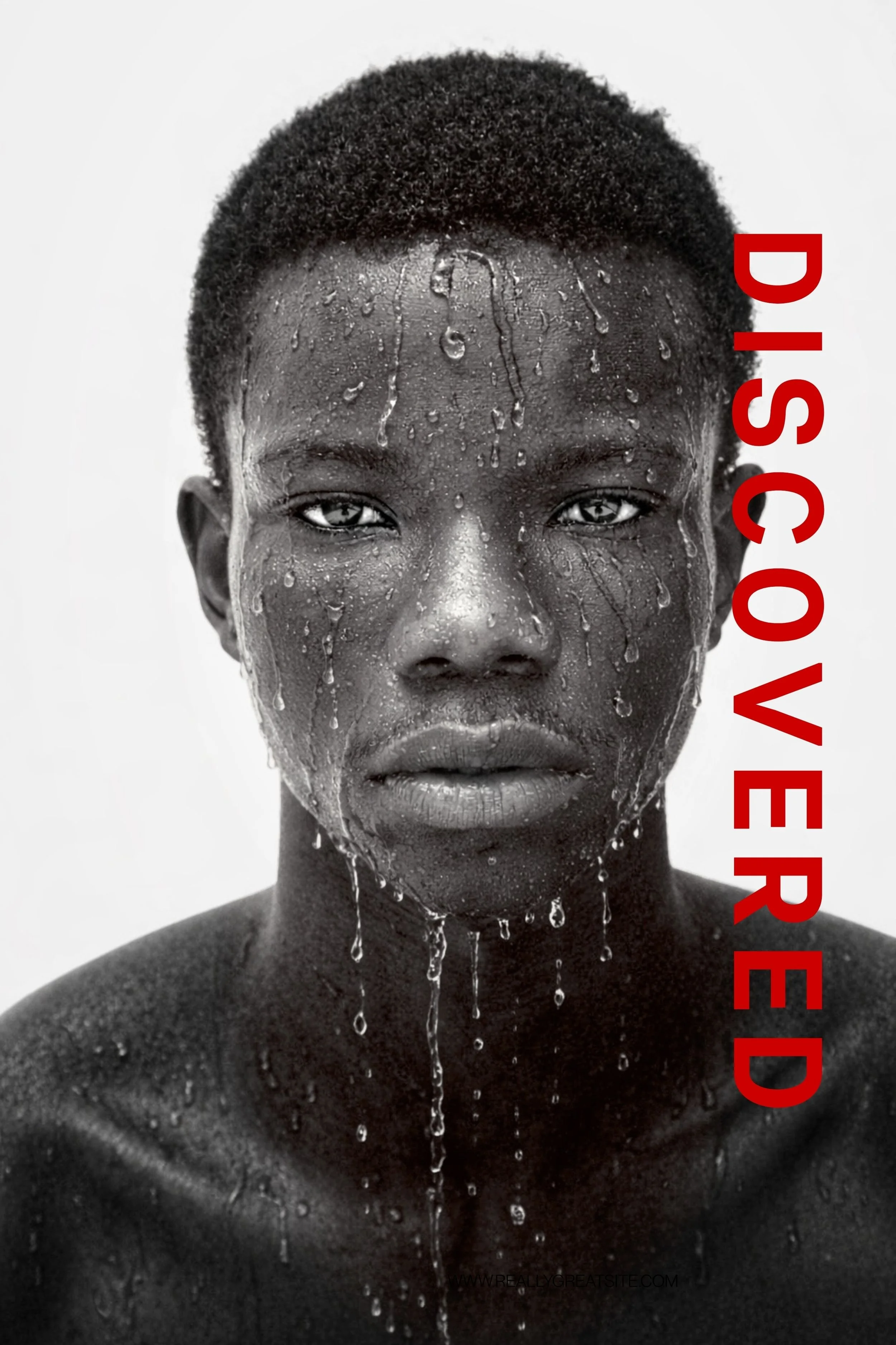 Photography by Riaan Swiegelaar. Black and white photo of a person with wet skin, water droplets on face and body, short curly hair, and intense gaze. The text 'DISCOVER' in bold red letters is vertically aligned on the right side of the image.