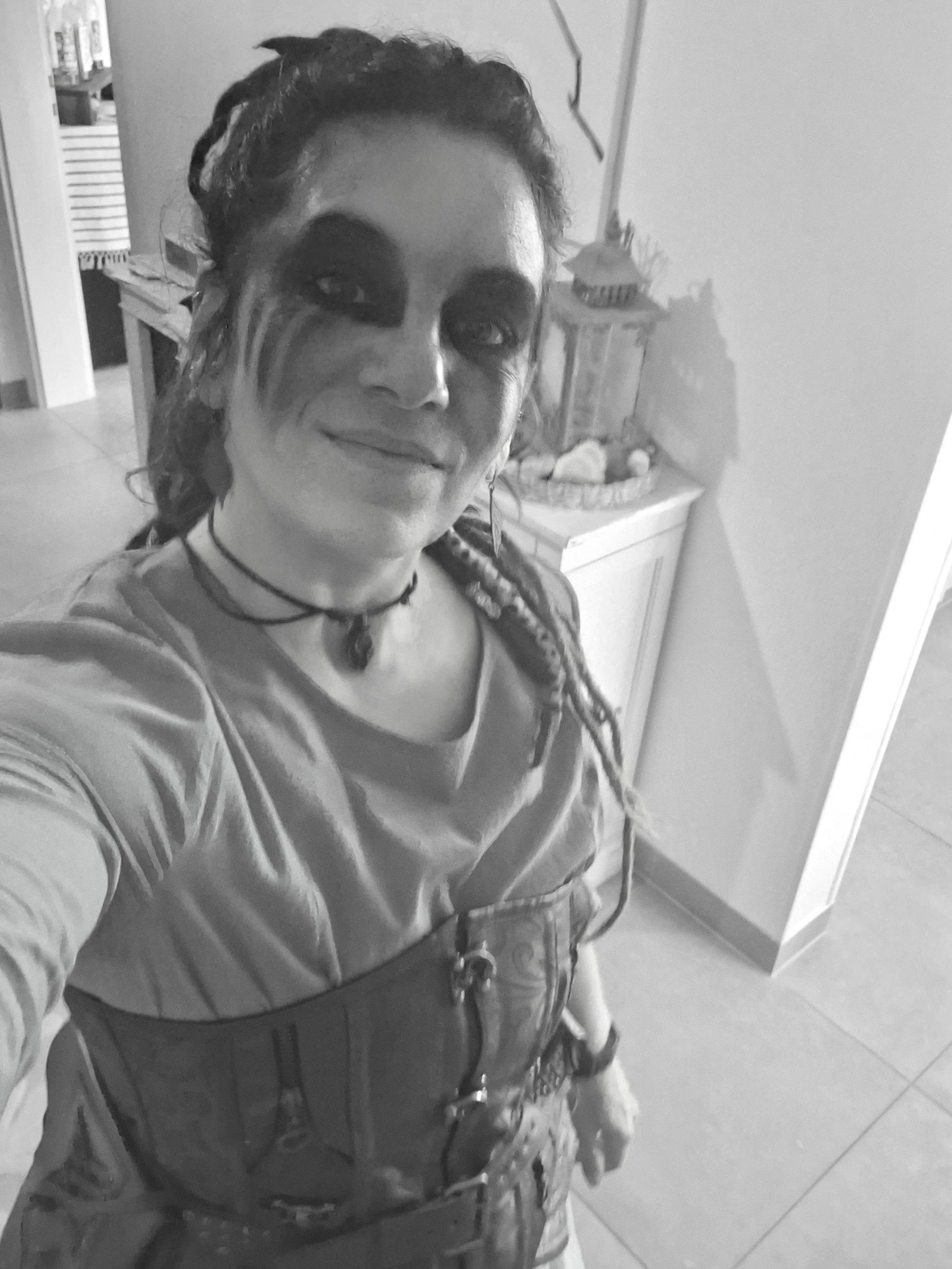 Selfie d'une personne  (Jessika Geoffroy)  avec un maquillage sombre autour des yeux et une expression souriante, portant un haut en satin et un corset en cuir évoquant les vickings.