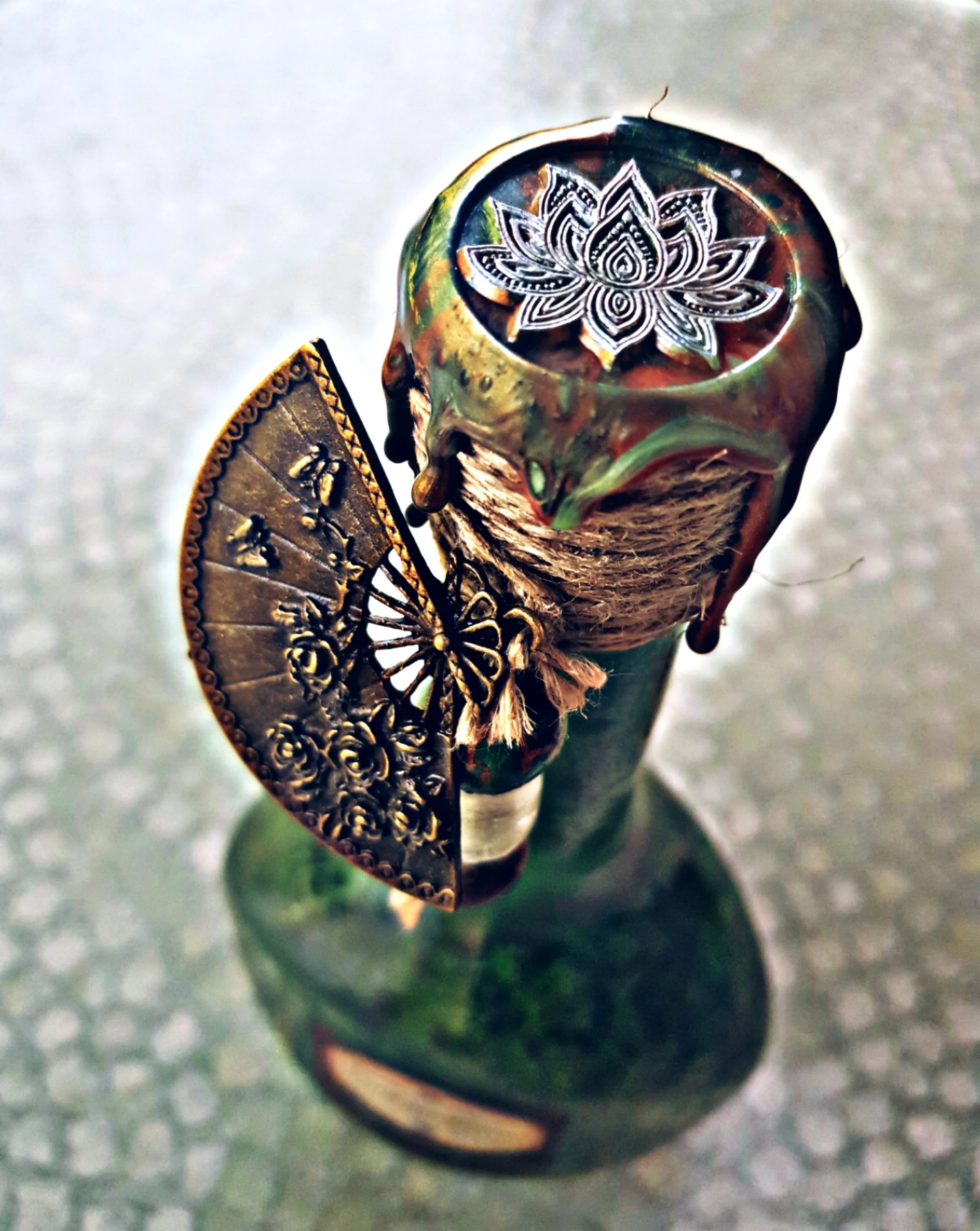 Bouteille avec décoration en métal doré, un éventail en métal doré et un motif de lotus blanc sur le bouchon.