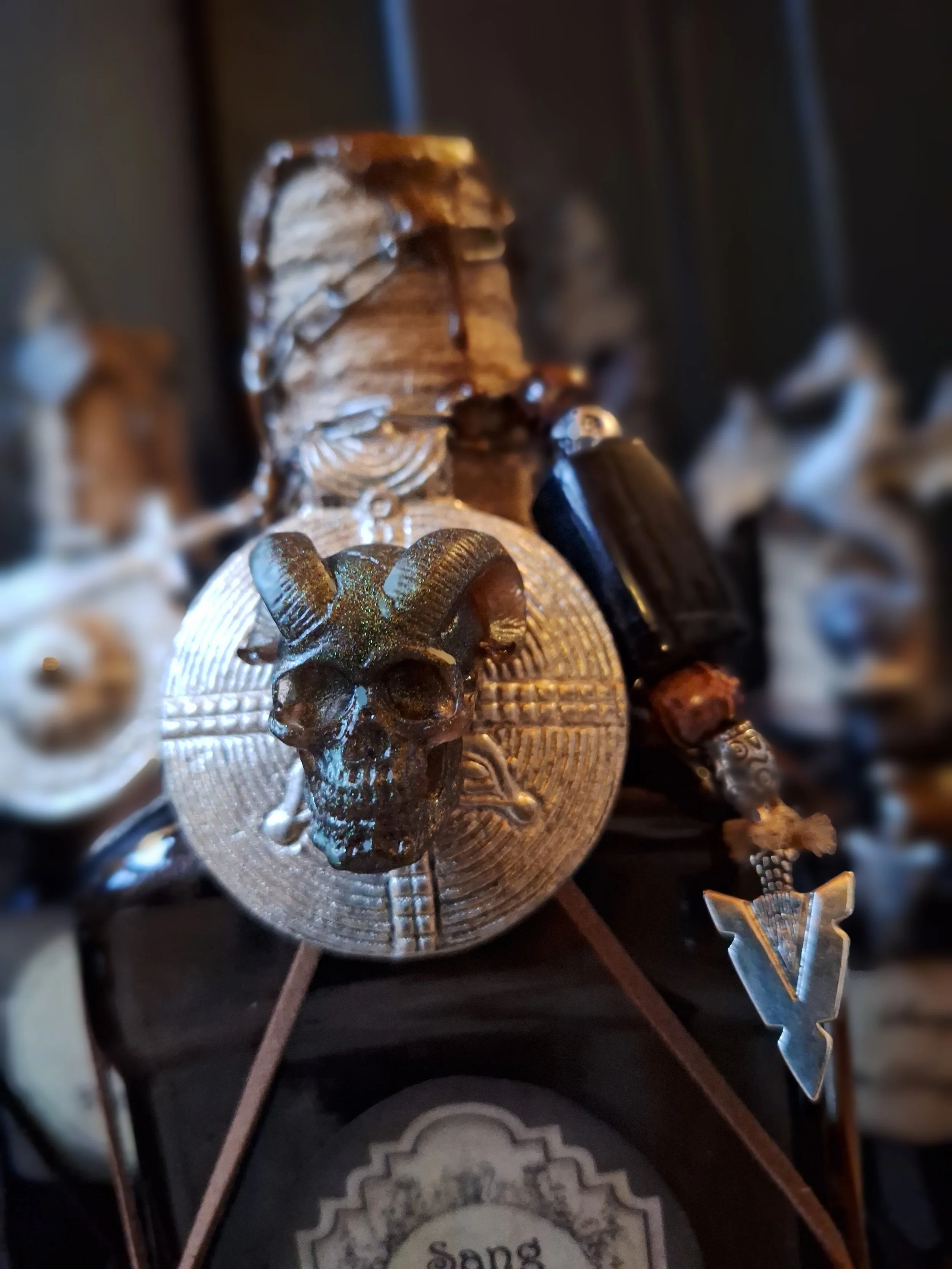 Une décoration médiévale avec un casque orné d'une tête de bélier, une plaque en métal avec un crâne de bélier, et une épée.