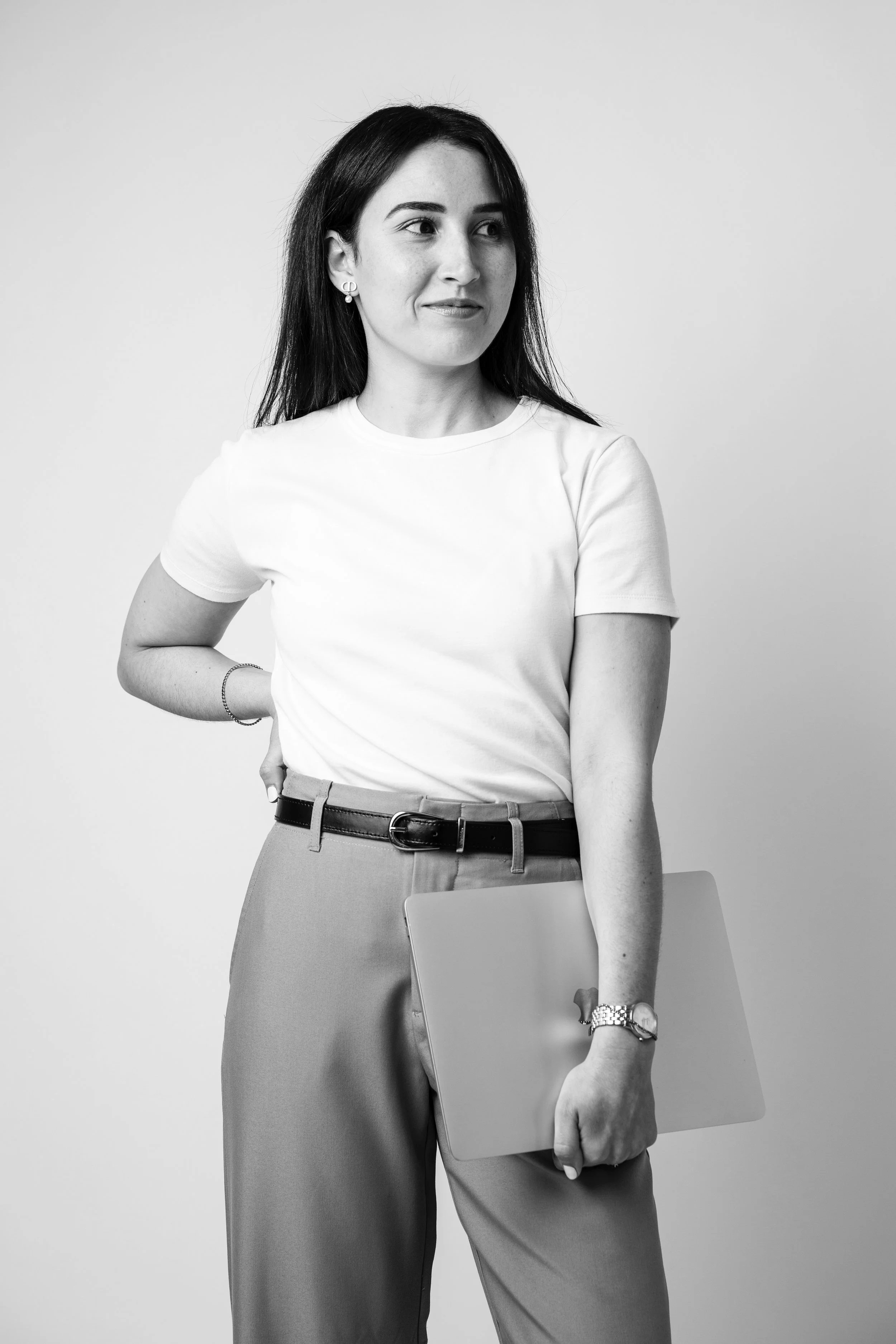Femme souriante, tenant un ordinateur portable.
