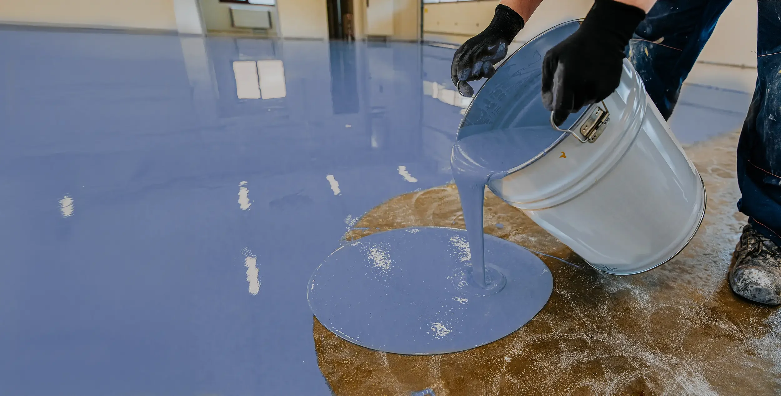 A worker pours a resin on the floor.