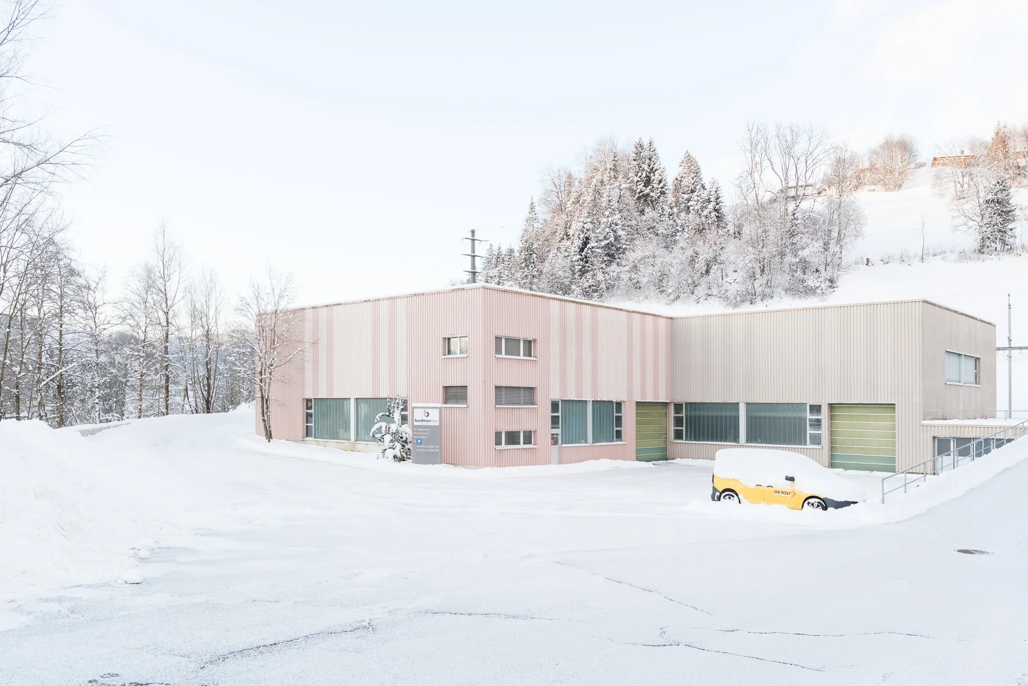 Schneebedecktes Gebäude und Bäume in einer Winterlandschaft mit klarem Himmel.